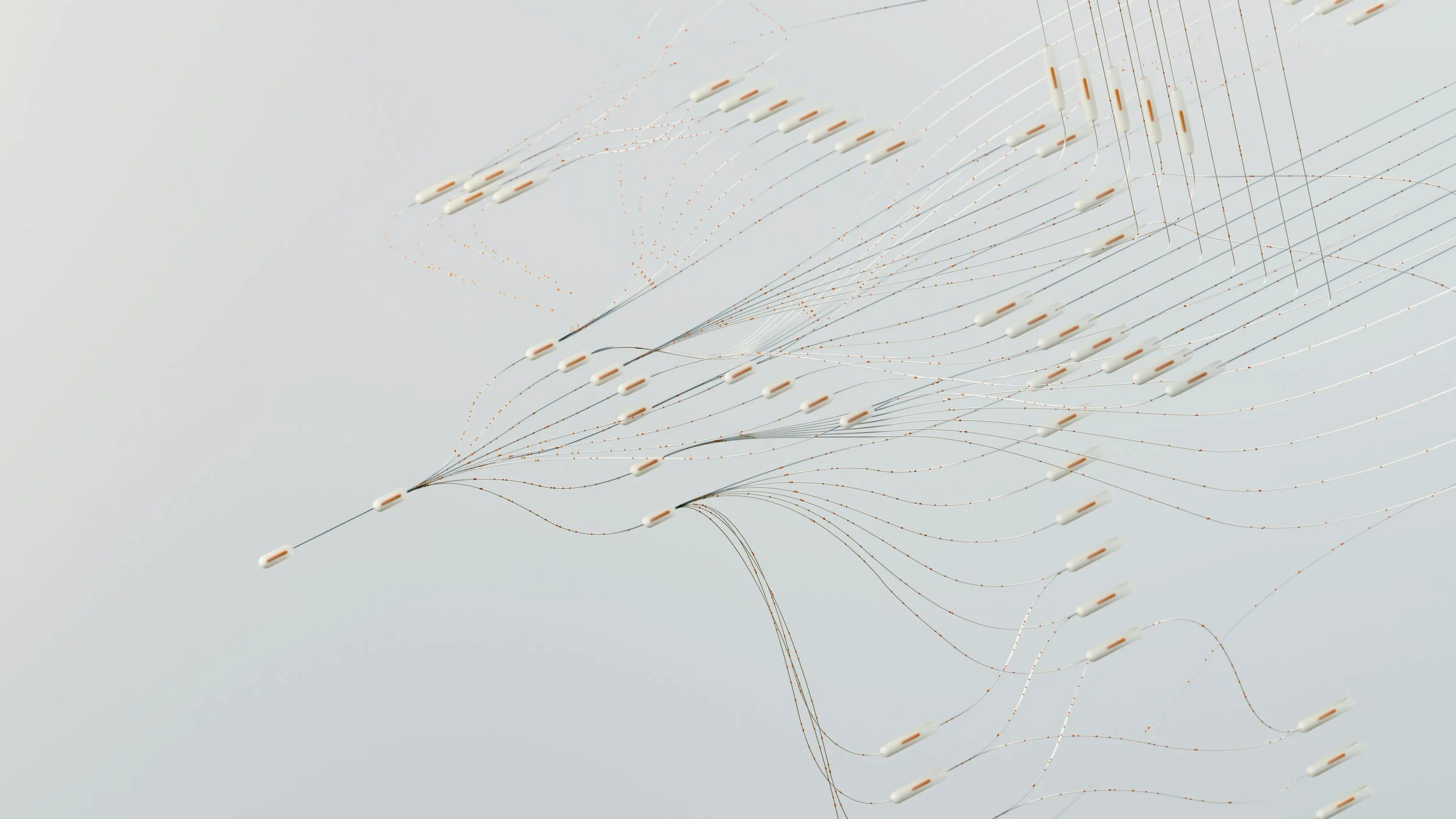 An abstract art installation with numerous thin wires and small white and orange capsules suspended, creating a flowing pattern.