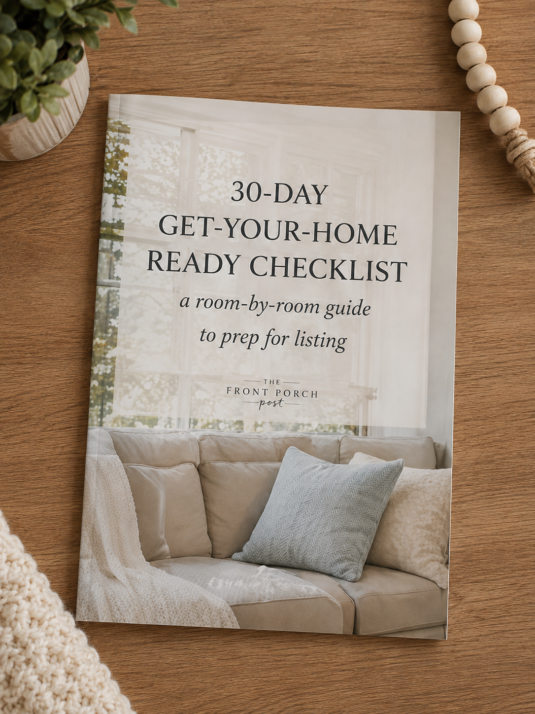 A house listing guide titled '30-Day Get-Your-Home Ready Checklist' on a wooden surface, with a potted plant and a beaded decoration nearby.