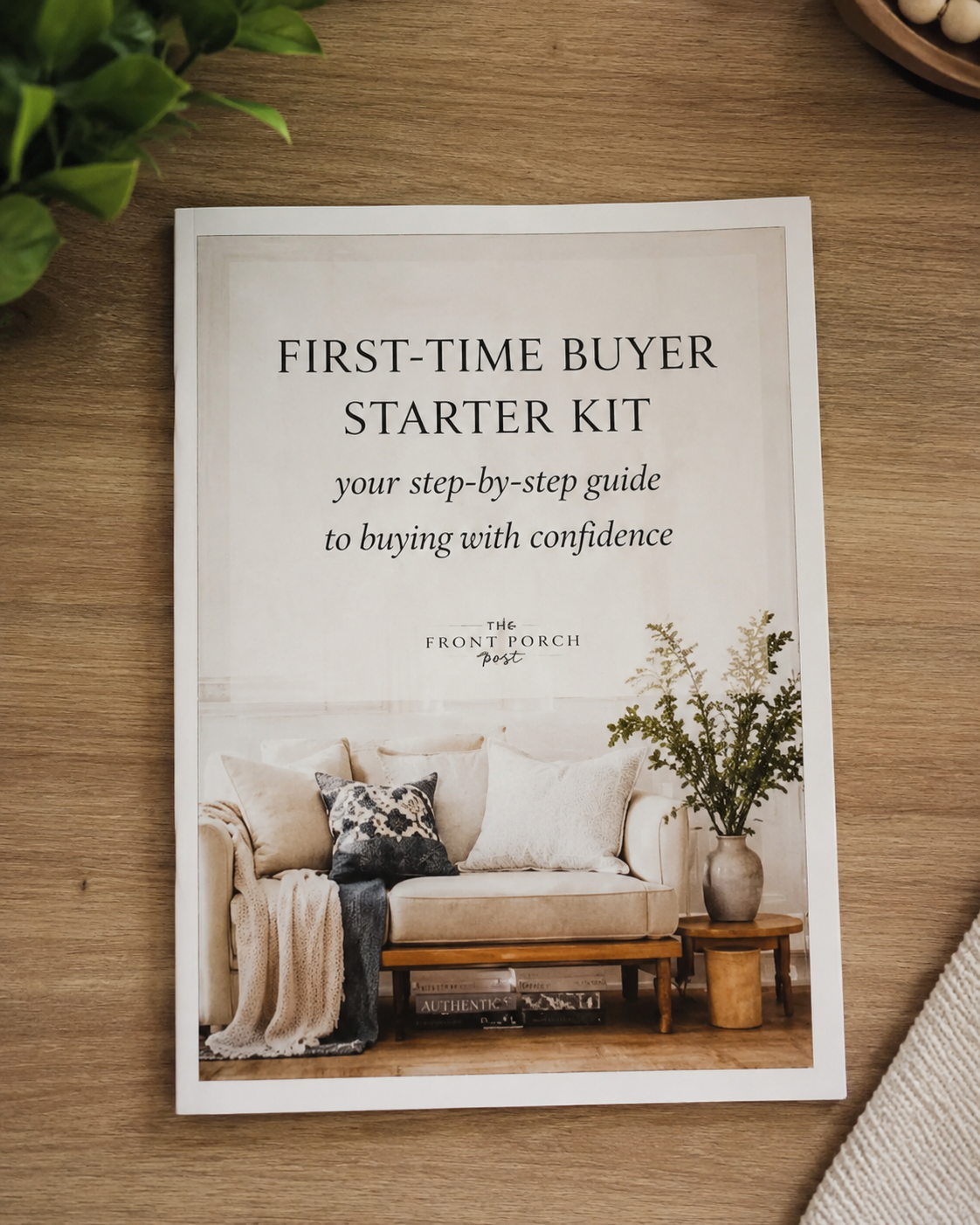 Book titled 'First-Time Buyer Starter Kit' on a wooden table, with a sofa and plant in the background.