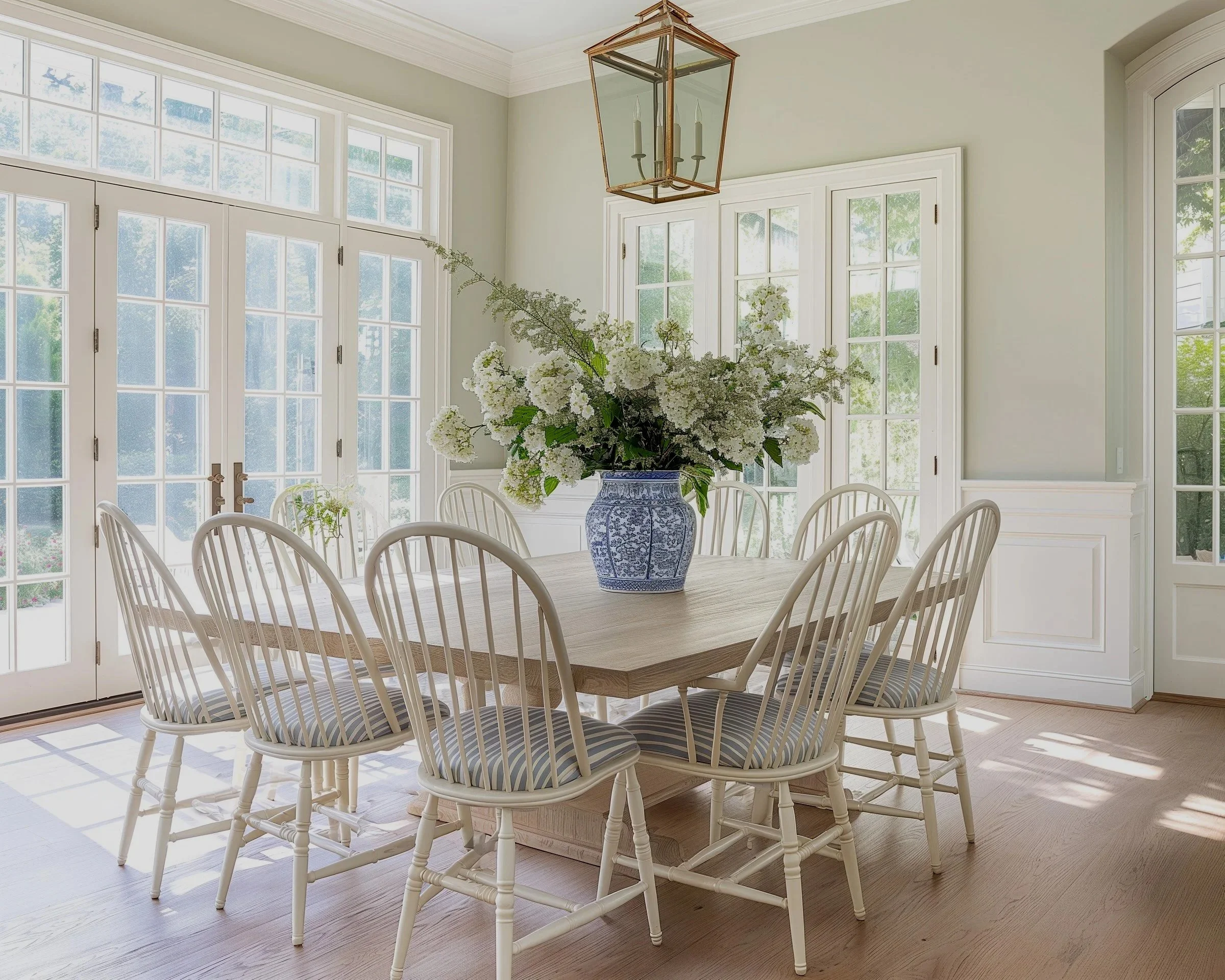 Coastal dining room with Windsor chairs, warm wood table, blue-and-white pottery and abundant flowers, offering a fresh interpretation of classic Lowcountry style.