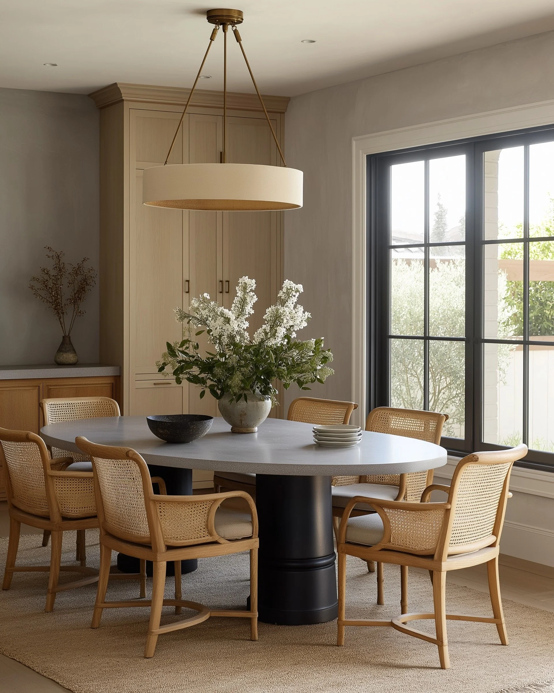 Warm, timeless dining room with natural wood, cane dining chairs, sculptural lighting and layered neutral finishes, reflecting Riley Baker Interiors’ refined Charleston interior design style and Charleston and sophisticated coastal living.