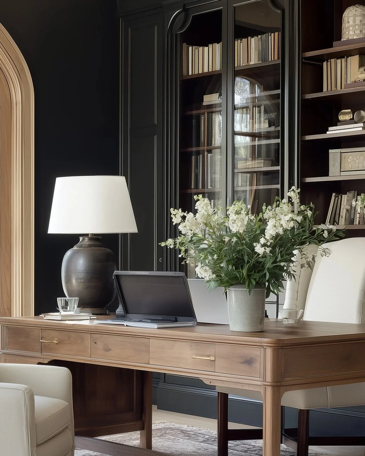 Layered home office with dark built-in cabinetry, warm wood desk, brass details, statement lighting and collected styling.