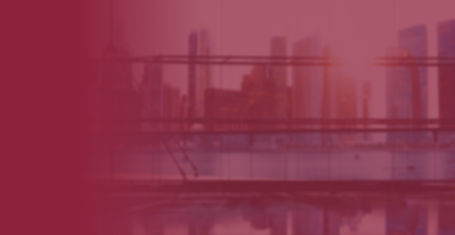 Blurred city skyline view from a bridge during sunset with pink and purple hues.