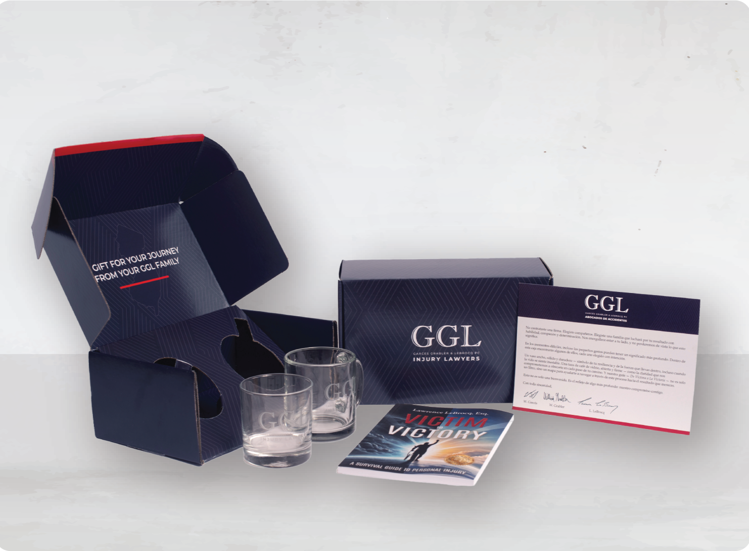 GGL Injury Lawyers promotional kit, including branded glasses, a brochure titled 'Victim Victory,' a box, and an informational card, all arranged on a white background.