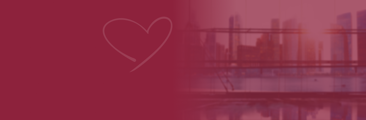 City skyline with tall buildings silhouette in pink and purple sky, with a bridge and water in the foreground.