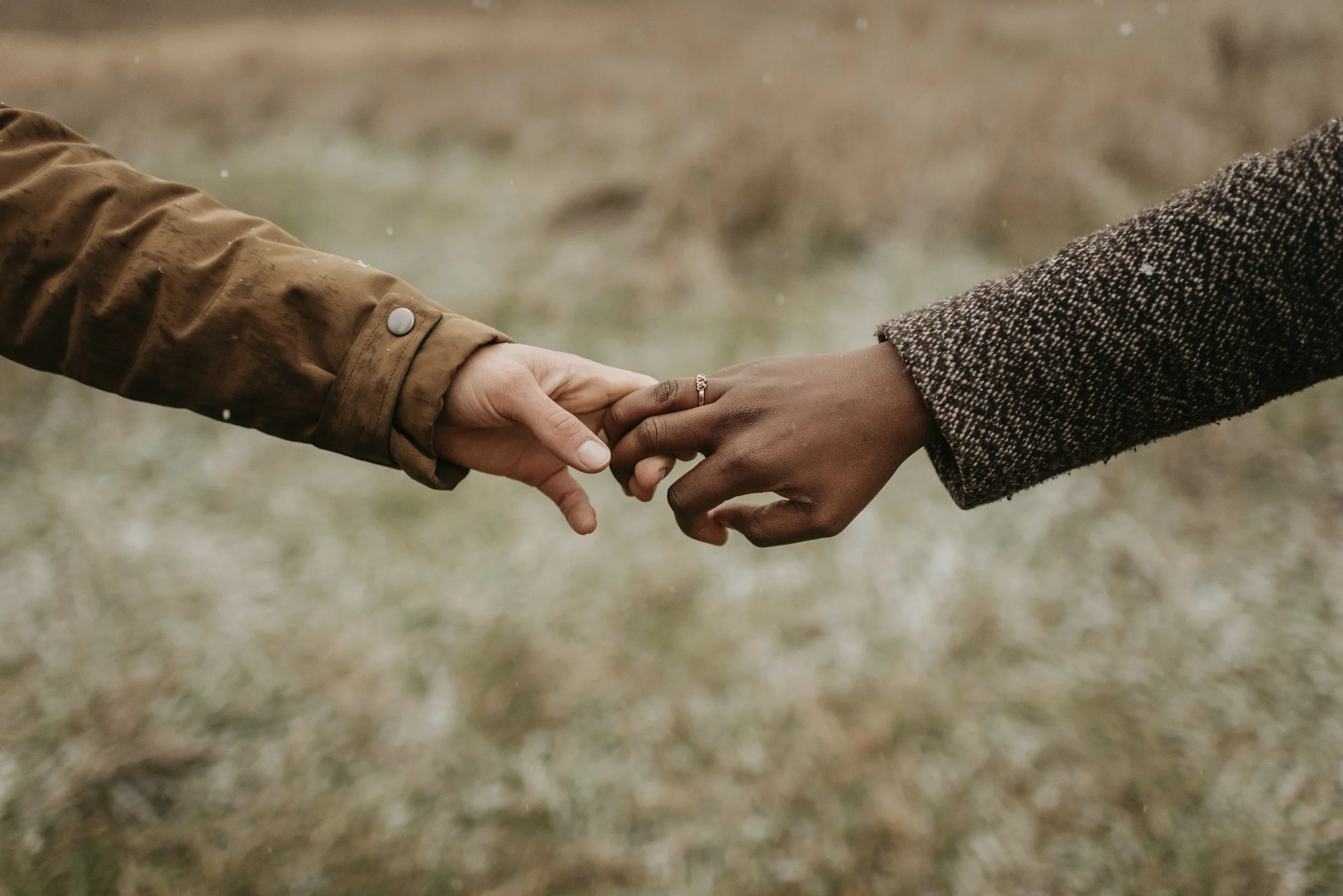 A couple reaching out, touching fingers, providing comfort to each other during a difficult time.