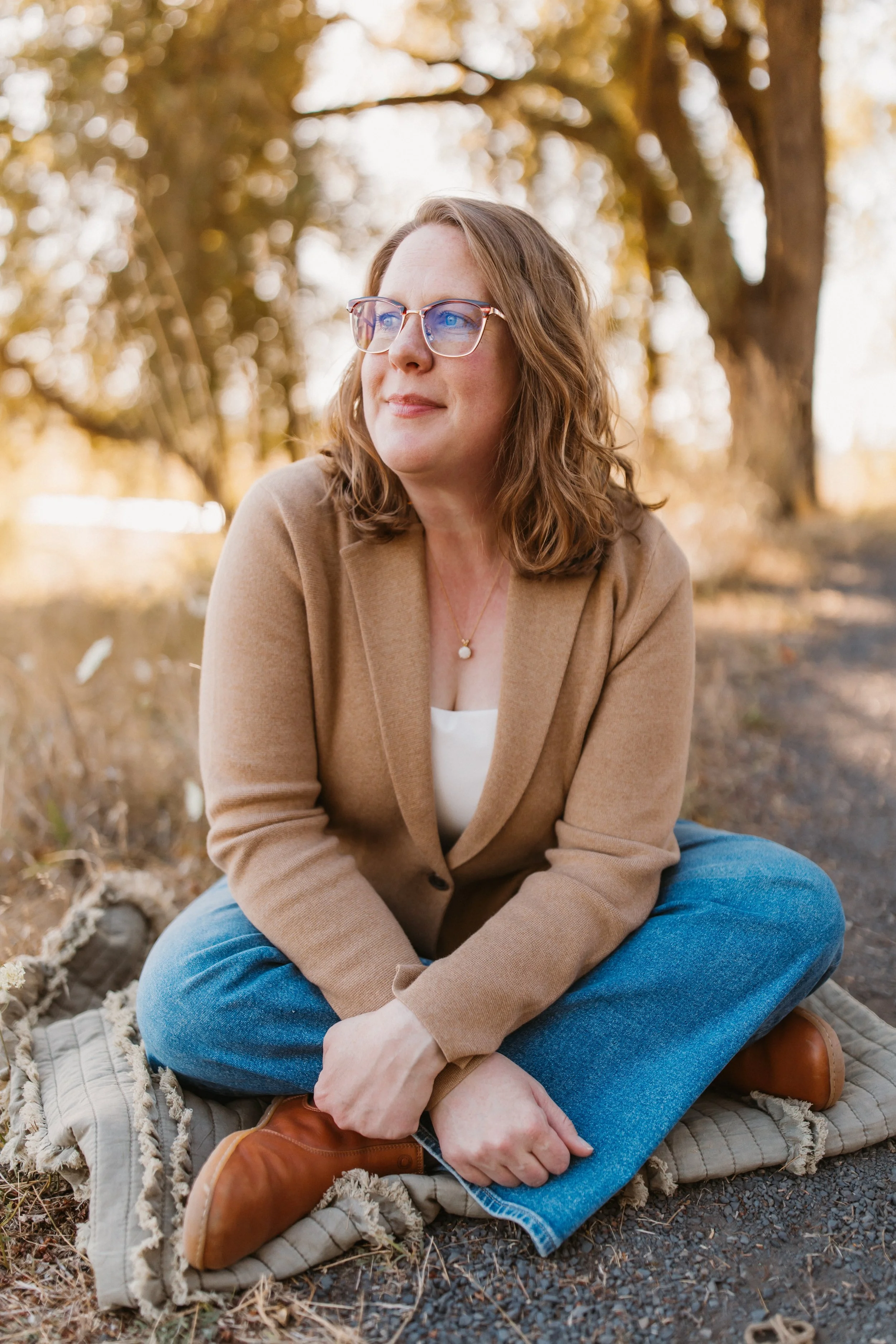 Ashley Sullivan sitting outdoors, reflecting in a quiet natural setting