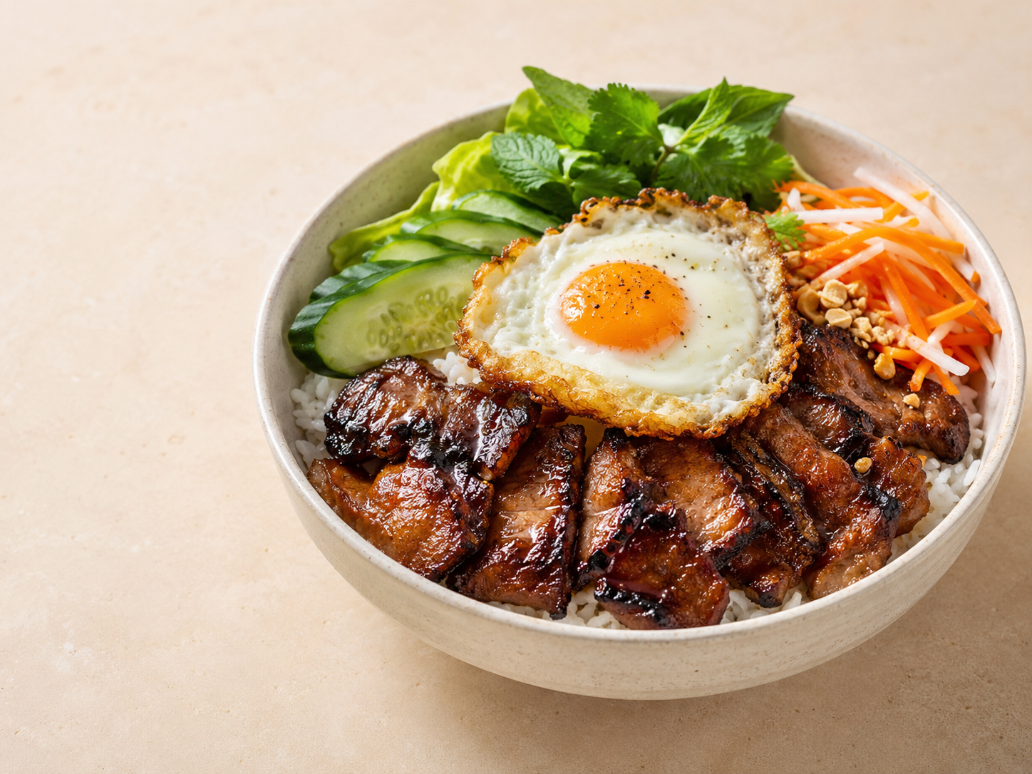 Bowl of rice topped with grilled pork, a fried egg, sliced cucumber, lettuce, shredded carrots, bean sprouts, cilantro, chopped peanuts, and sauce.