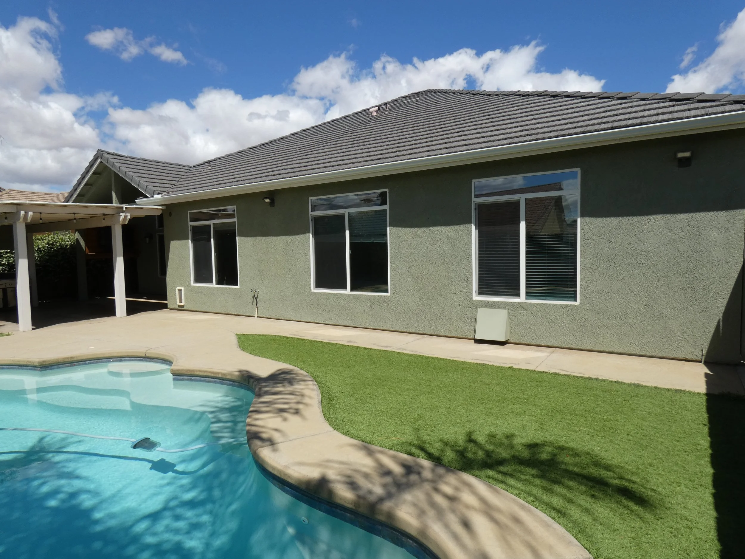 Backyard with a swimming pool and attractive synthetic lawn for minimal maintenance.