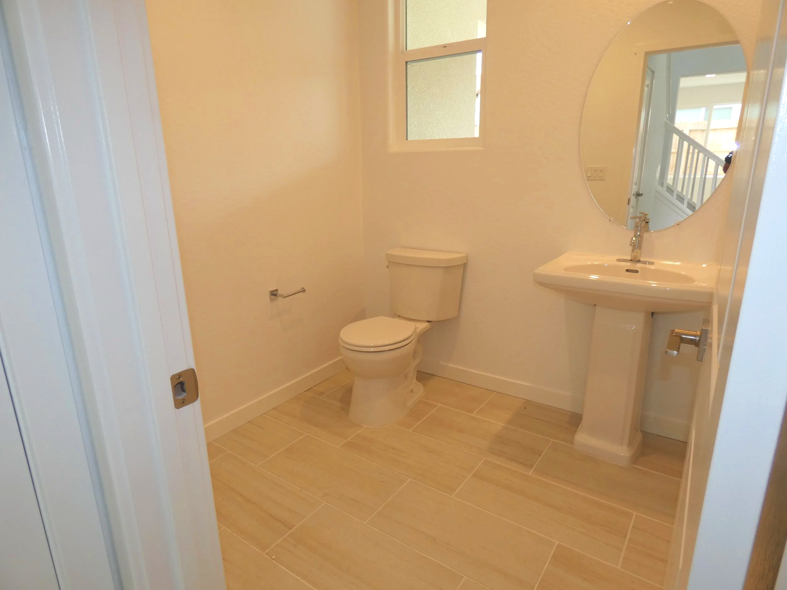 A decent sized half bathroom with a cute pedestal sink with a mirror above it.