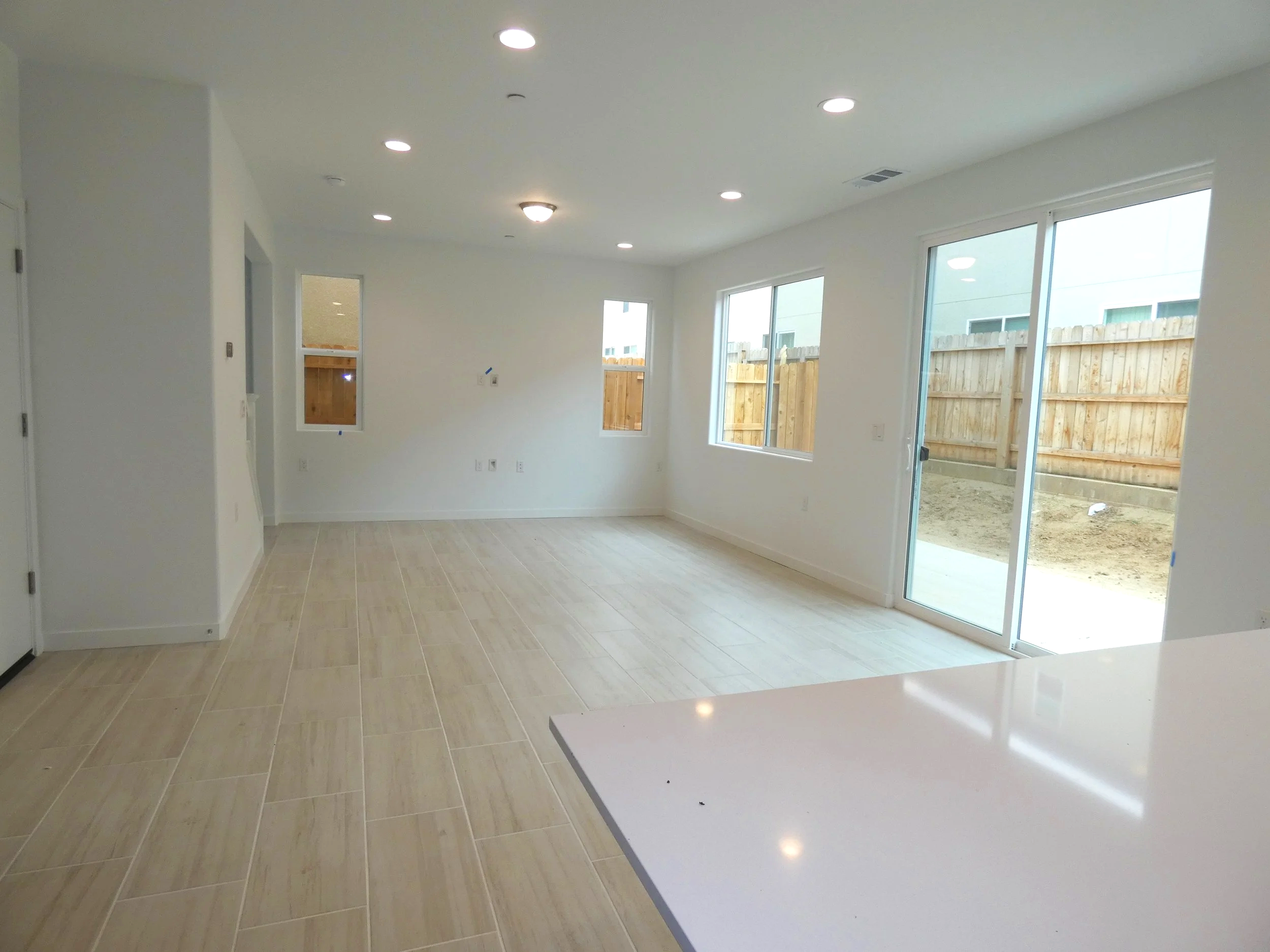 A dining room area with a family room beyond - all with natural light and recessed lighting.