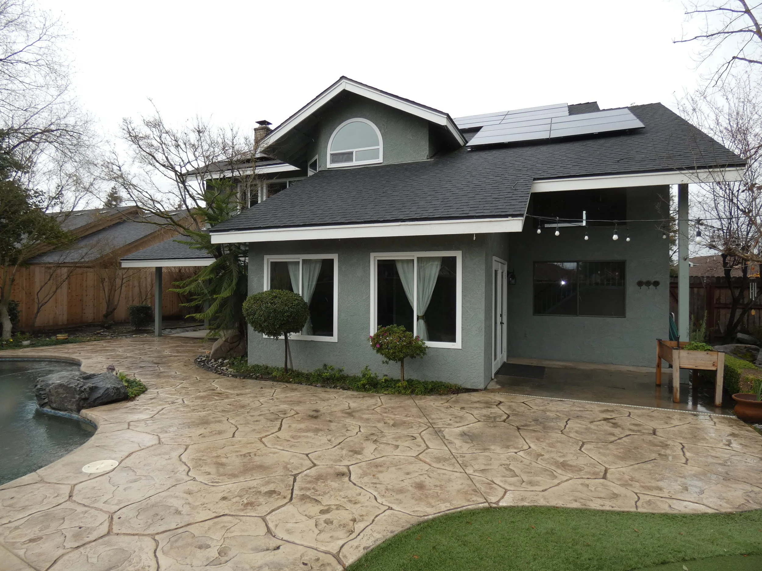 An ultra clean rear yard with covered patio, stamped concrete, and solar panels to save on electricity.