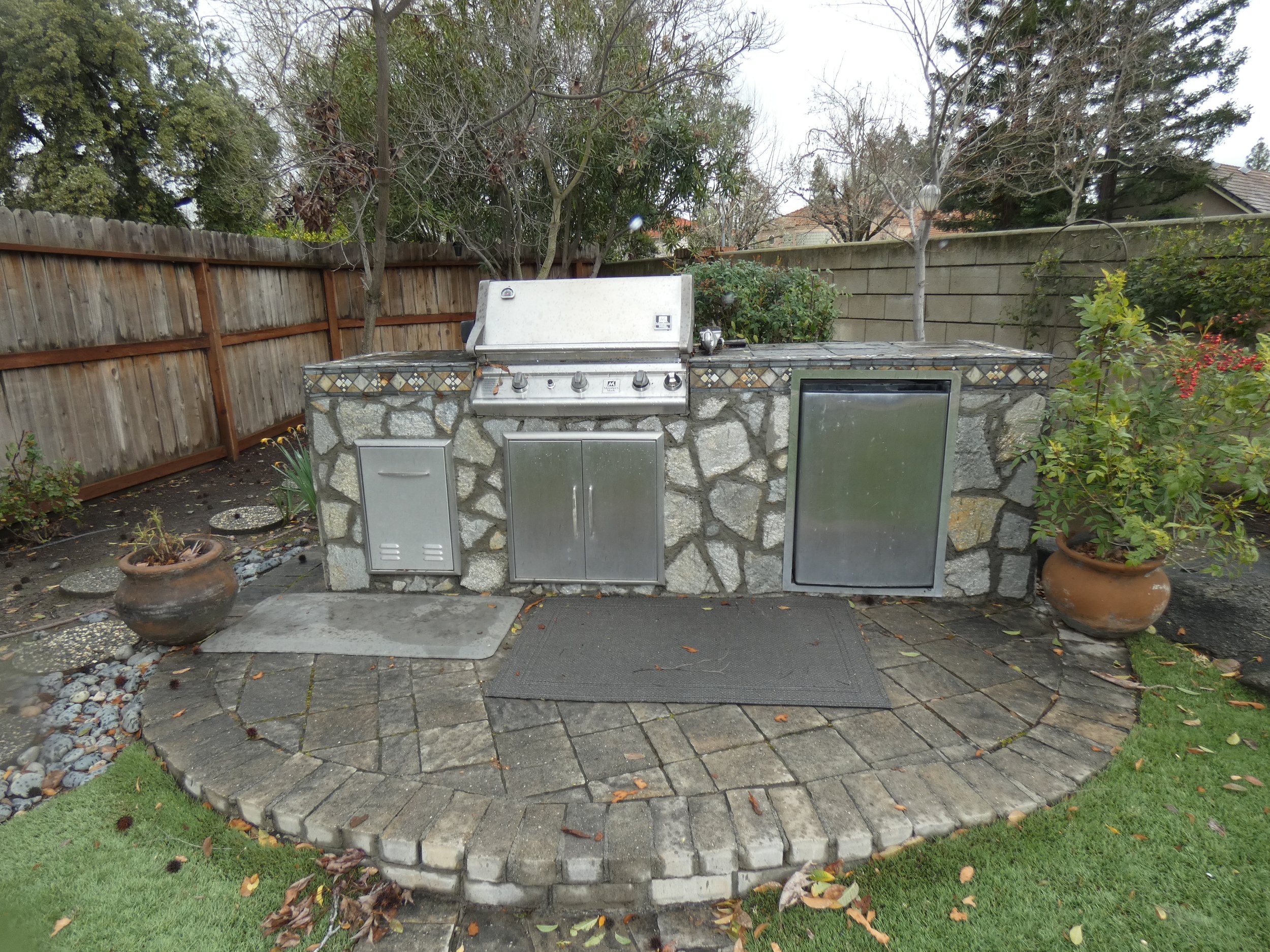 An outdoor kitchen with stone facia and brick decking.