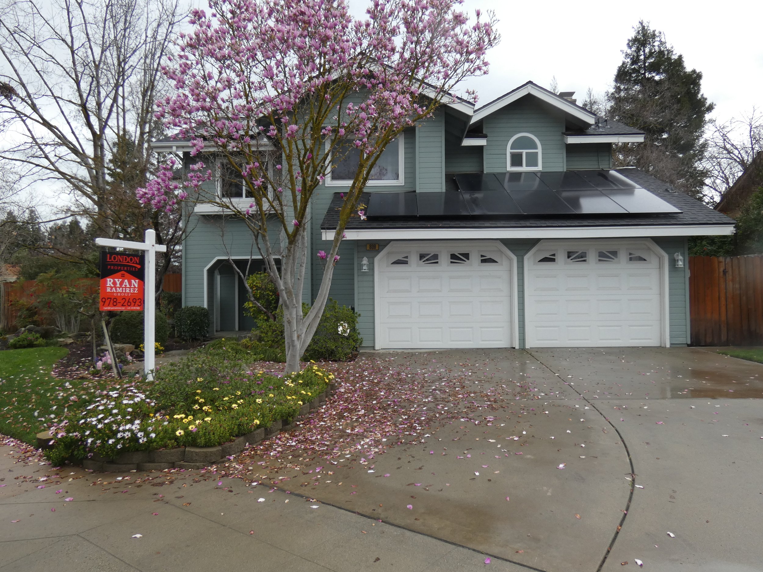 A cape cod style two-story home with a built-in two car garage and attractive landscaping.