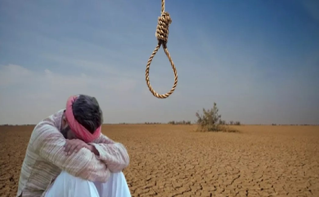 A man sitting on the dry, cracked ground of a barren desert, with his head resting on his knees and arms crossed. Above him, there is a noose hanging from a rope in the sky.