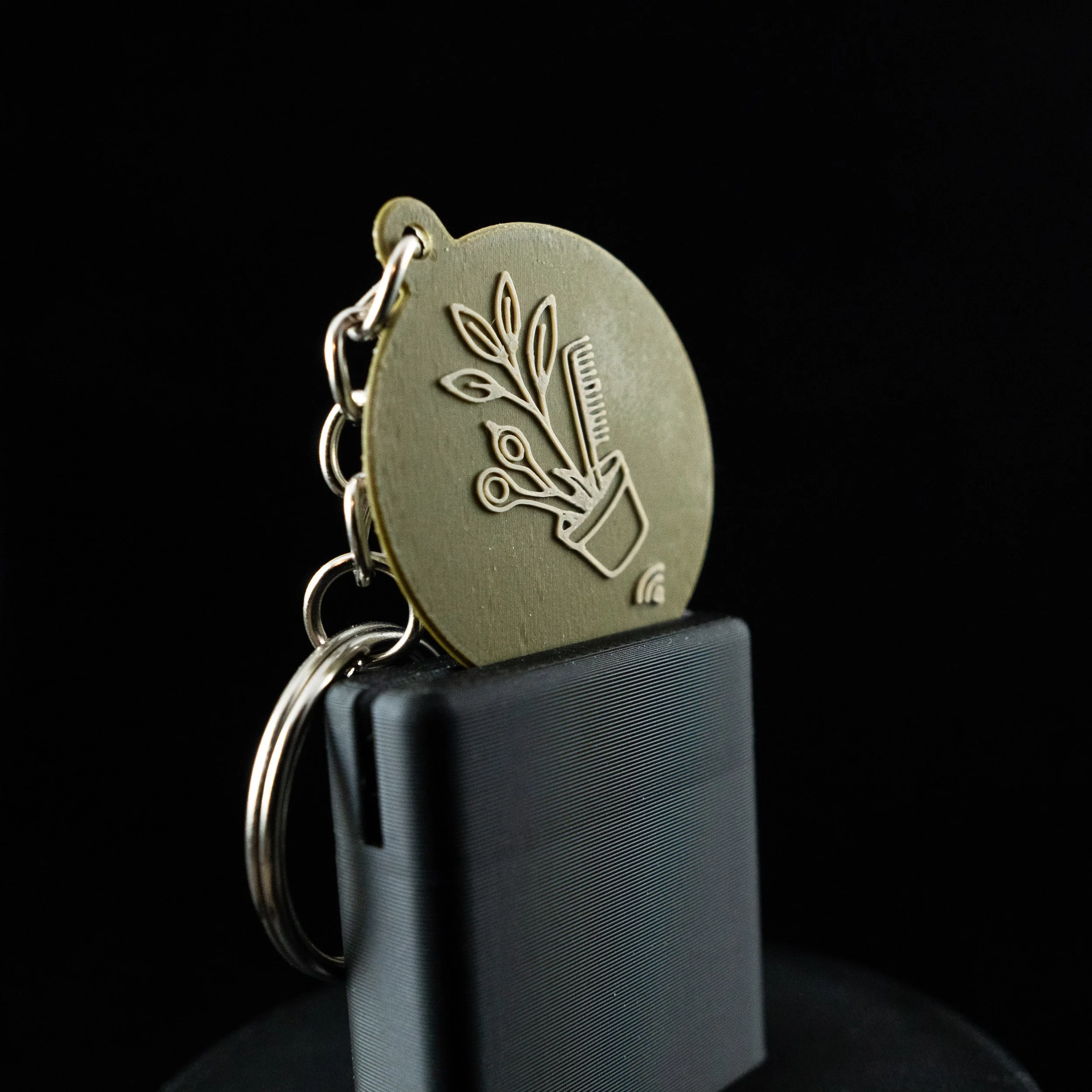 Close-up of a NFC Keychain with engraved designs and text, set against a black background.