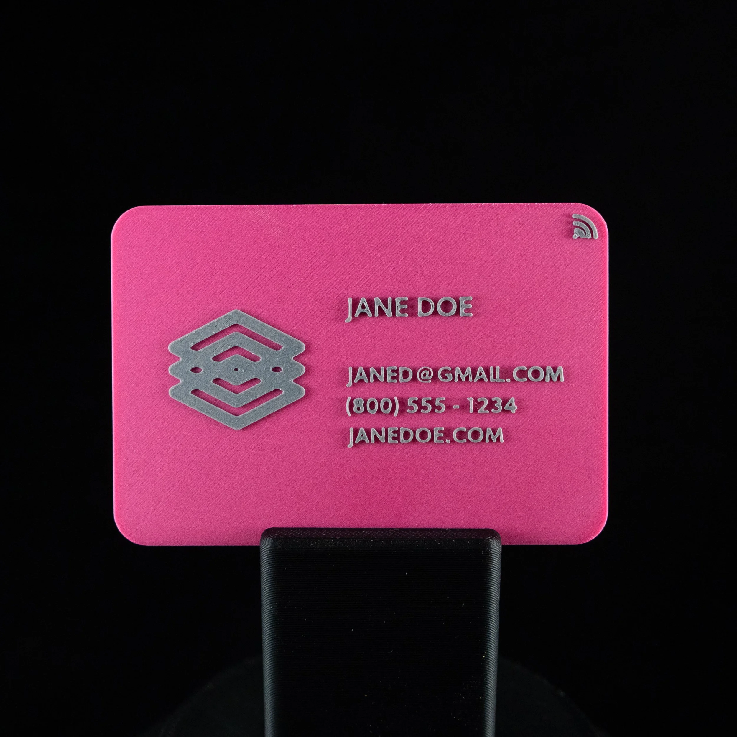 A pink NFC business card with grey text that has name, email address, phone number, and website.