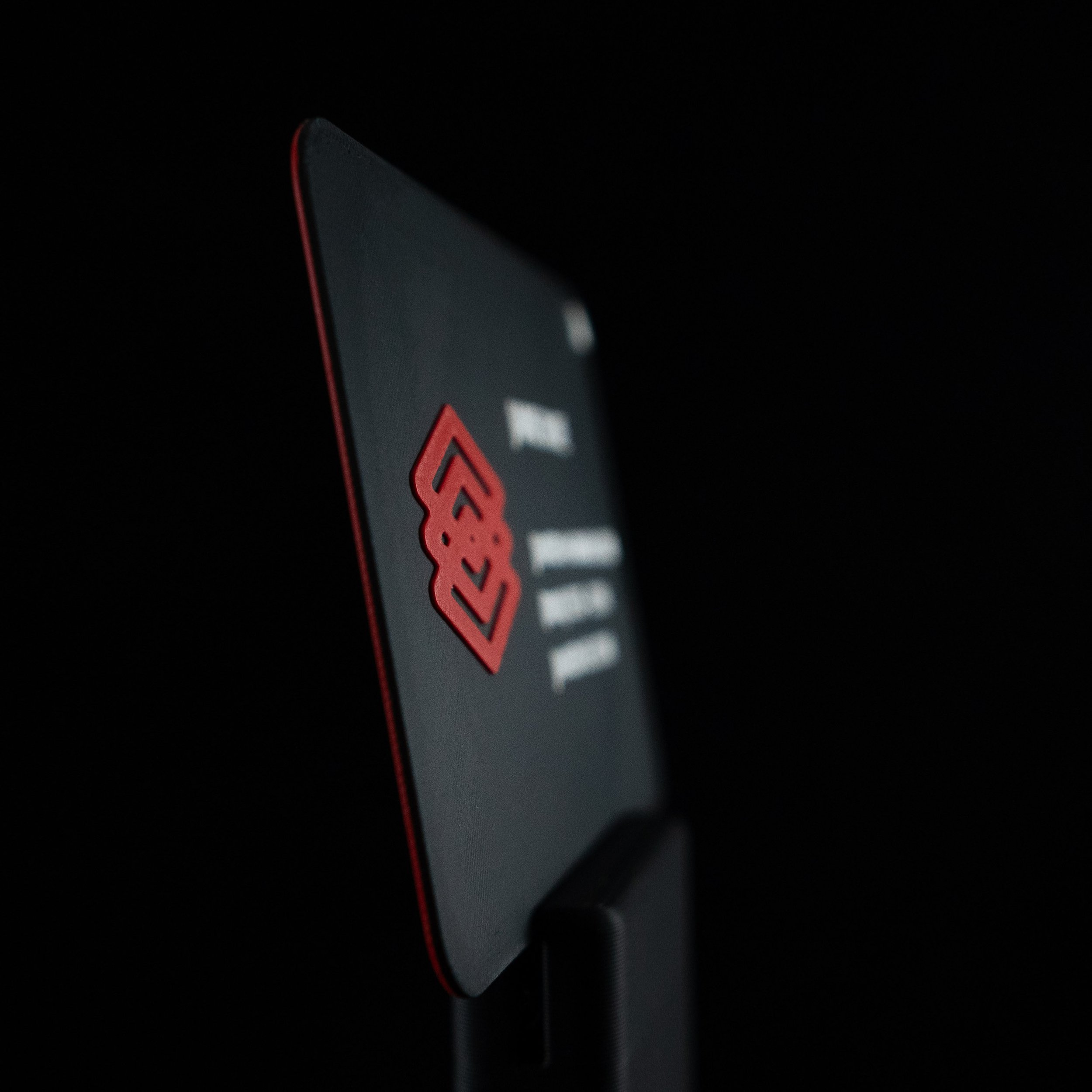 Close-up of a 3d printed business card with a red symbol, set against a dark background.
