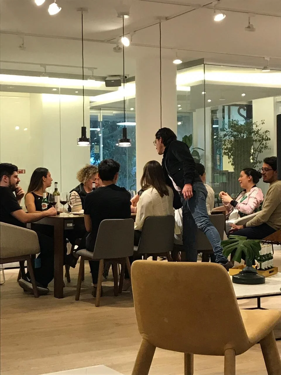 Grupo de personas sentado en una mesa en un restaurante, con un camarero sirviendo y algunas bebidas en la mesa.