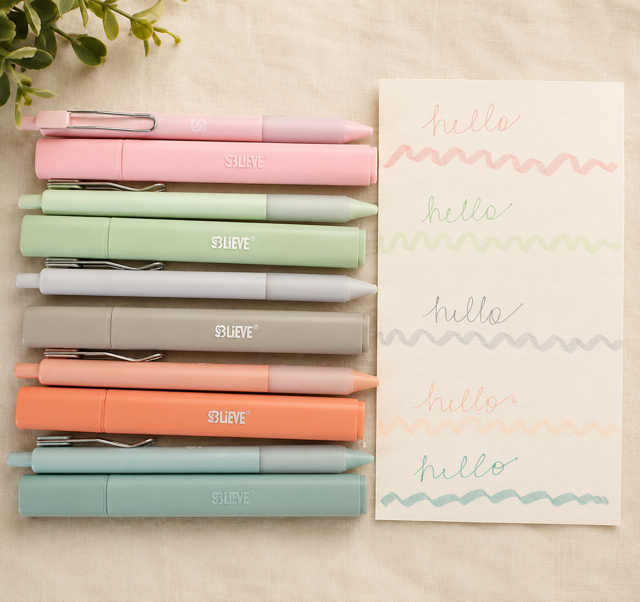 Eight pastel-colored markers arranged on a beige surface next to a piece of paper decorated with multicolored 'hello' written in cursive and wavy lines.