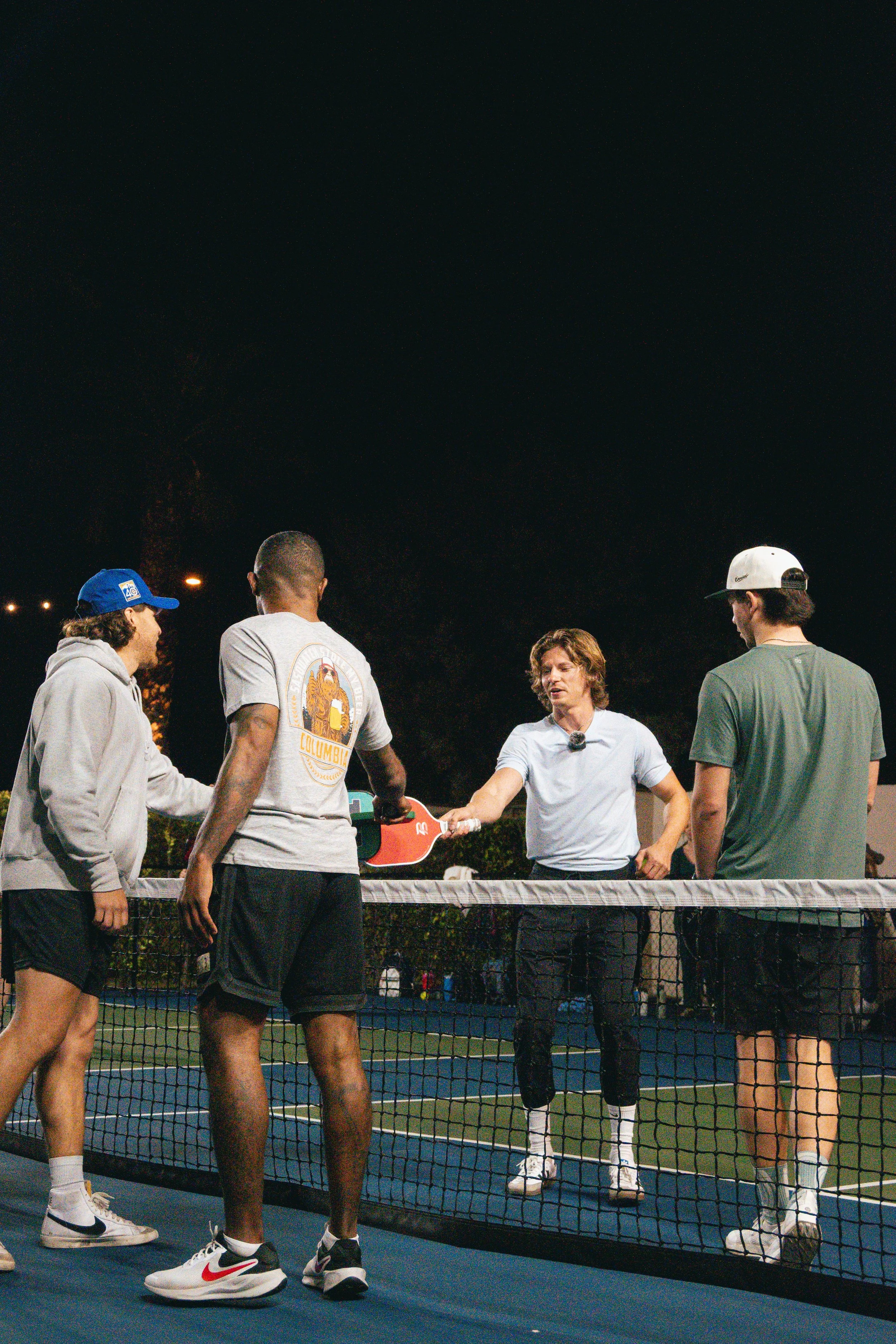 4 Pickleball players meeting at the net after completing a pickleball match.