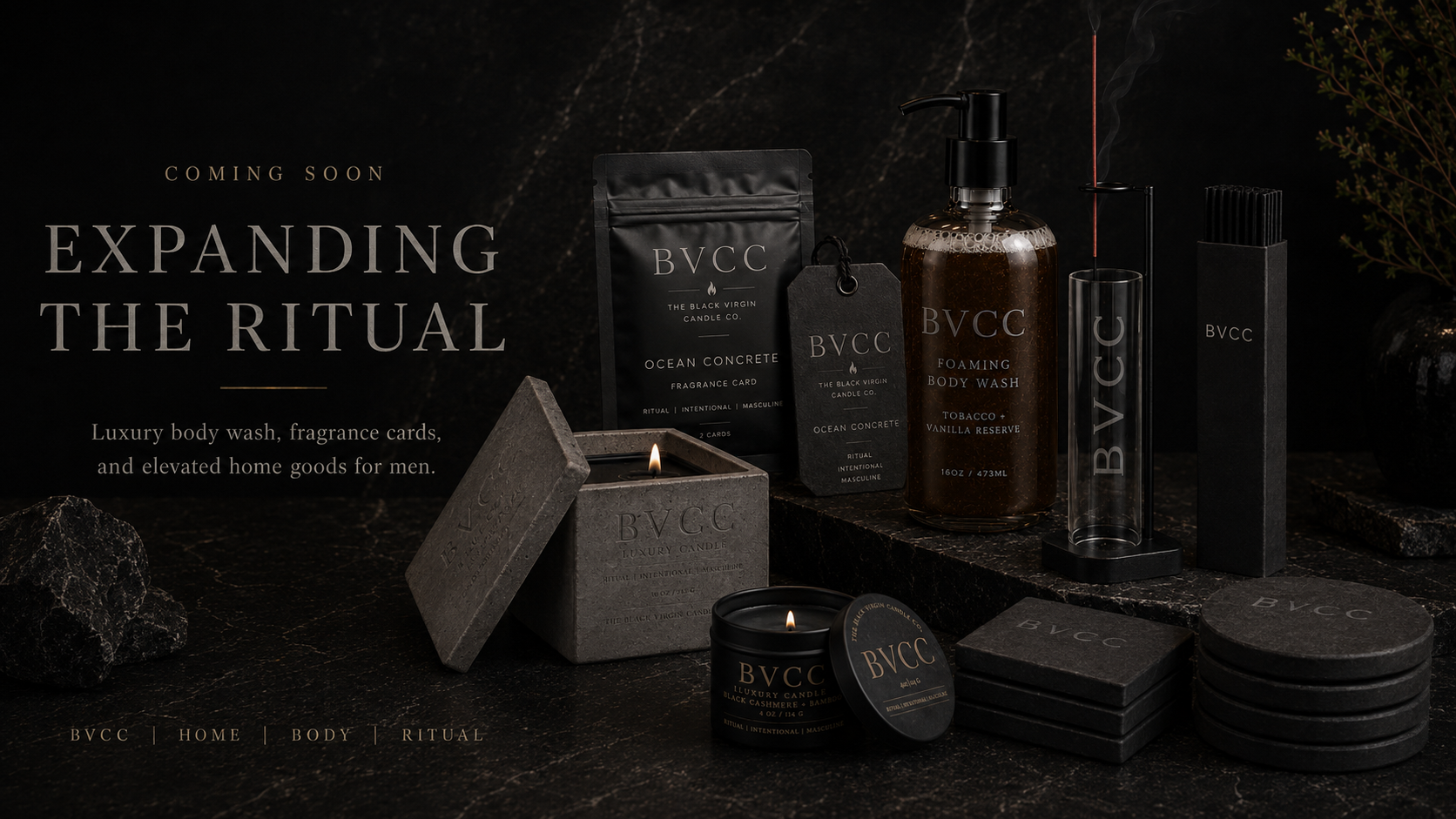 Luxury men's body care products including candles, body wash, fragrance cards, and coasters on a dark stone surface with rocks and plants in the background, promoting expanding rituals.