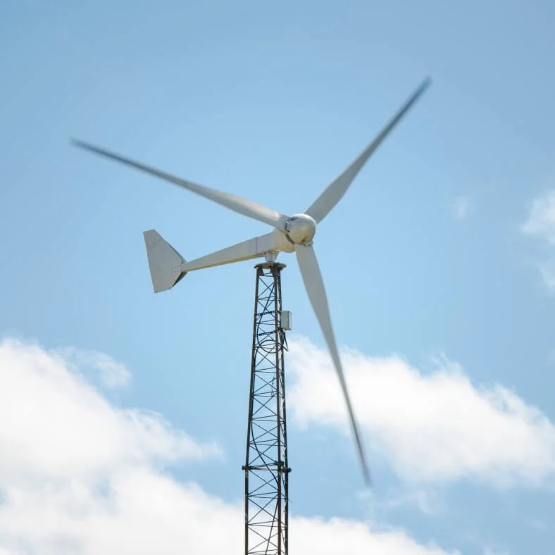 Aerogenerador sobre una torre de metal bajo cielo con nubes.