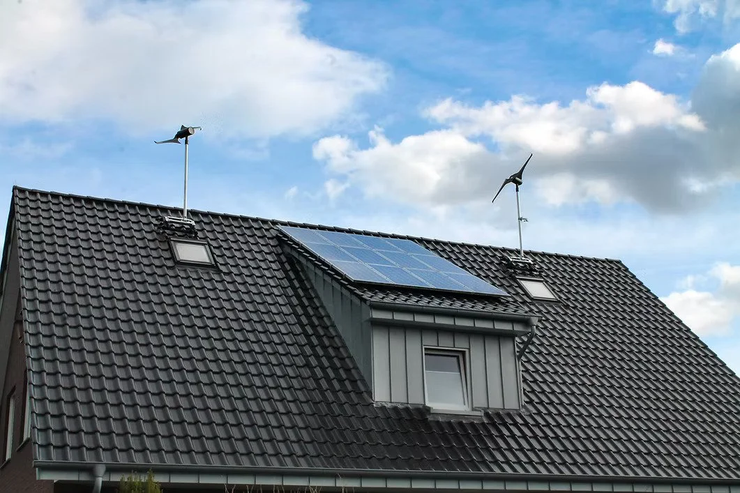 Techo de una casa con paneles solares y aerogeneradores.