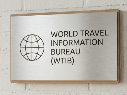 Metal sign with a globe icon and the text 'World Travel Information Bureau (WTIB)' mounted on a white brick wall.