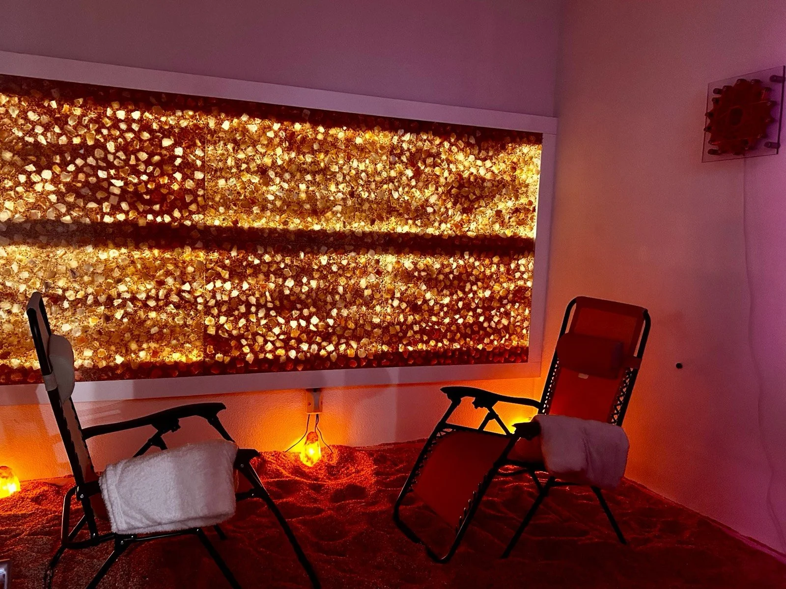Glowing Himalayan salt wall and lounge chairs in the salt room at Just Be Wellness & Beauty in Windsor, CA