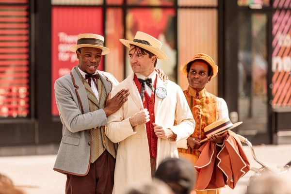 Production photo of The Kitty Knox Plays. Three people dressed in vintage clothing standing outside a building, smiling and talking to each other.