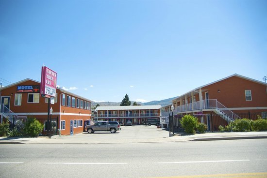 Exterior view of a two-story motel with parking lot, under a clear blue sky.