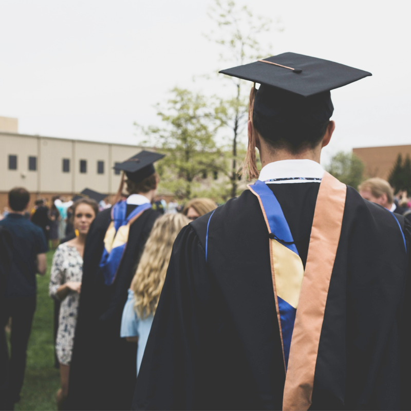 Graduates in caps and gowns participating in a commencement ceremony outdoors.