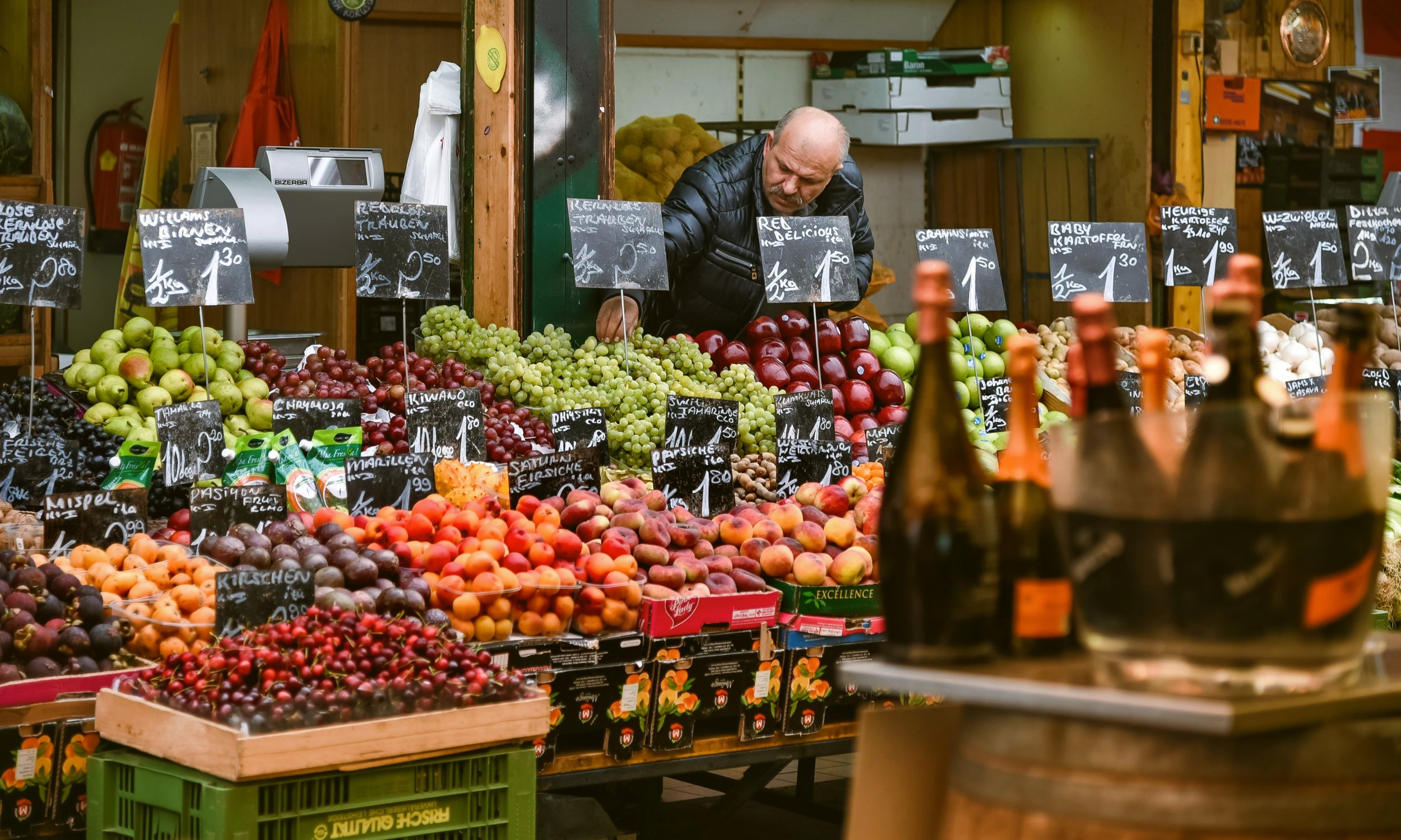 Naschmarkt stall with colorful fruits and vegetables and bottles on the right, Vienna.