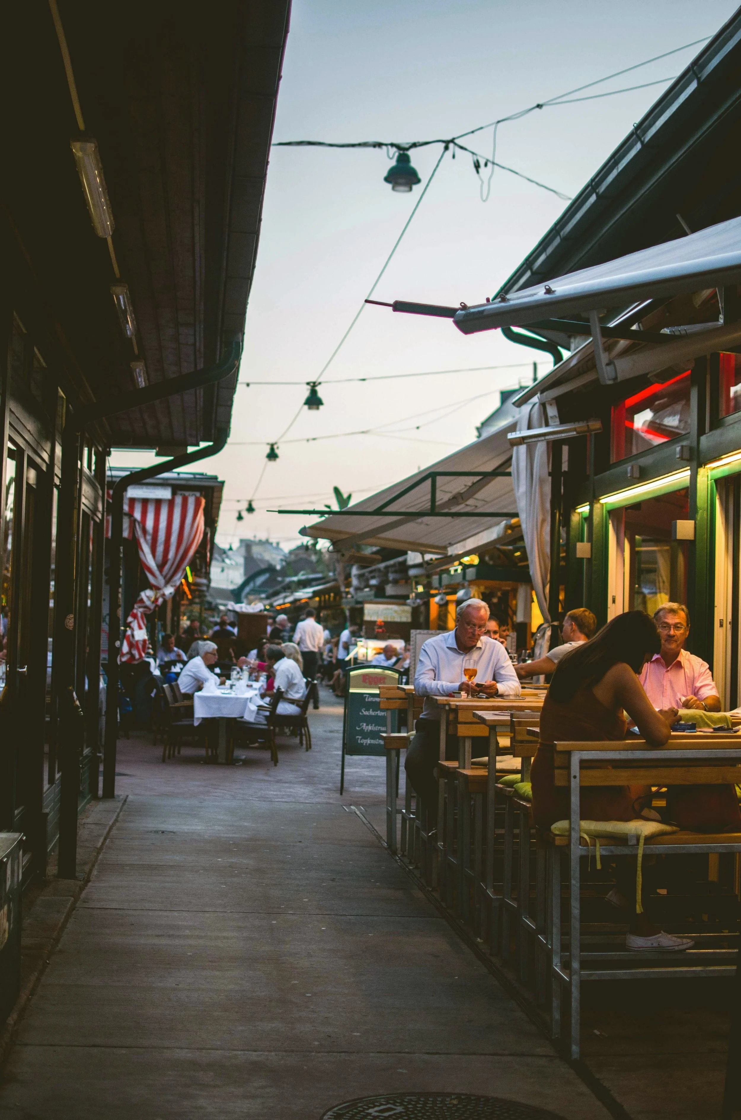 Outdoor market stalls lit up along Naschmarkt at dusk, Vienna.