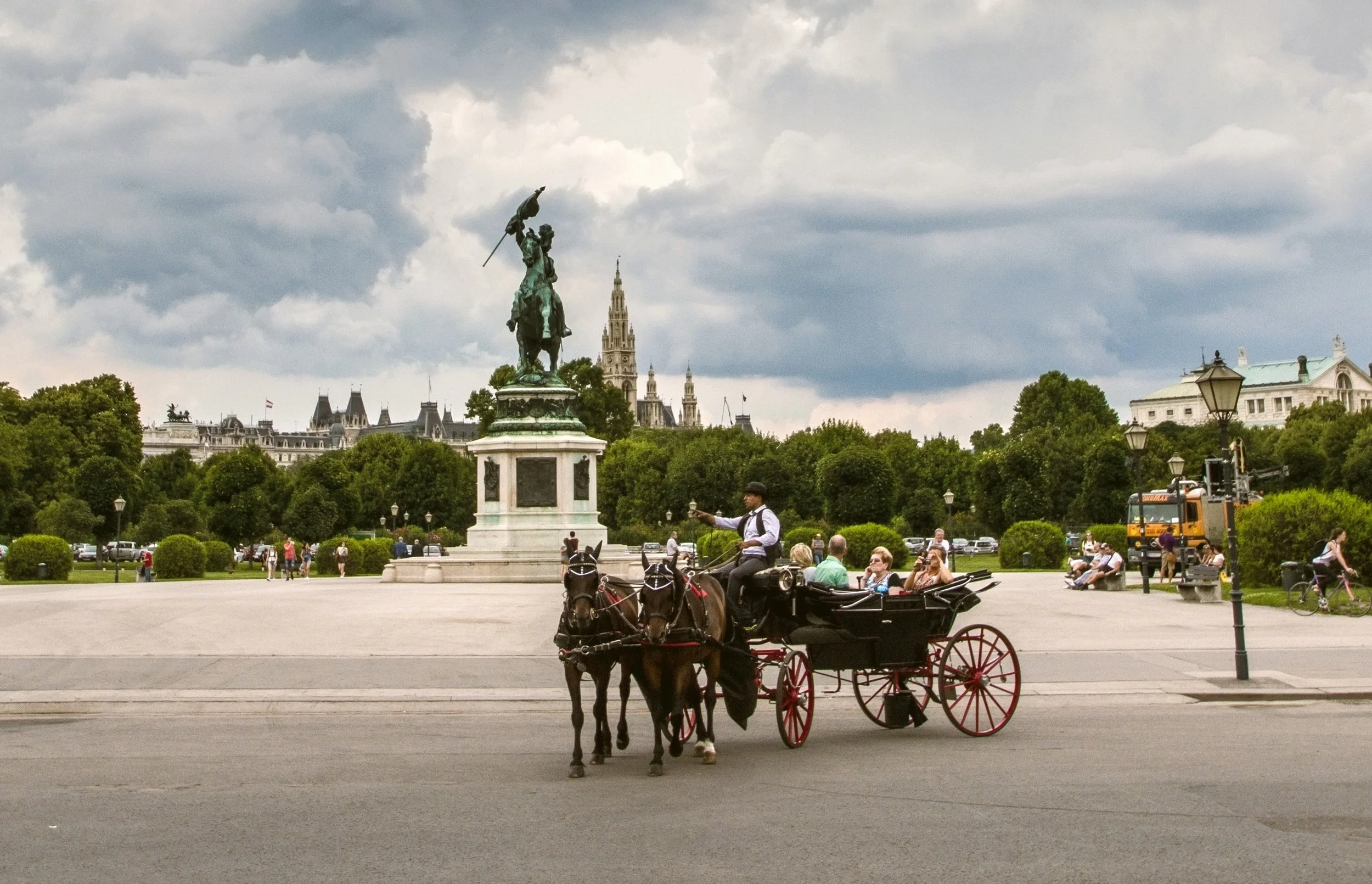 Horse-drawn carriage passing a monument in Heldenplatz, Vienna.
