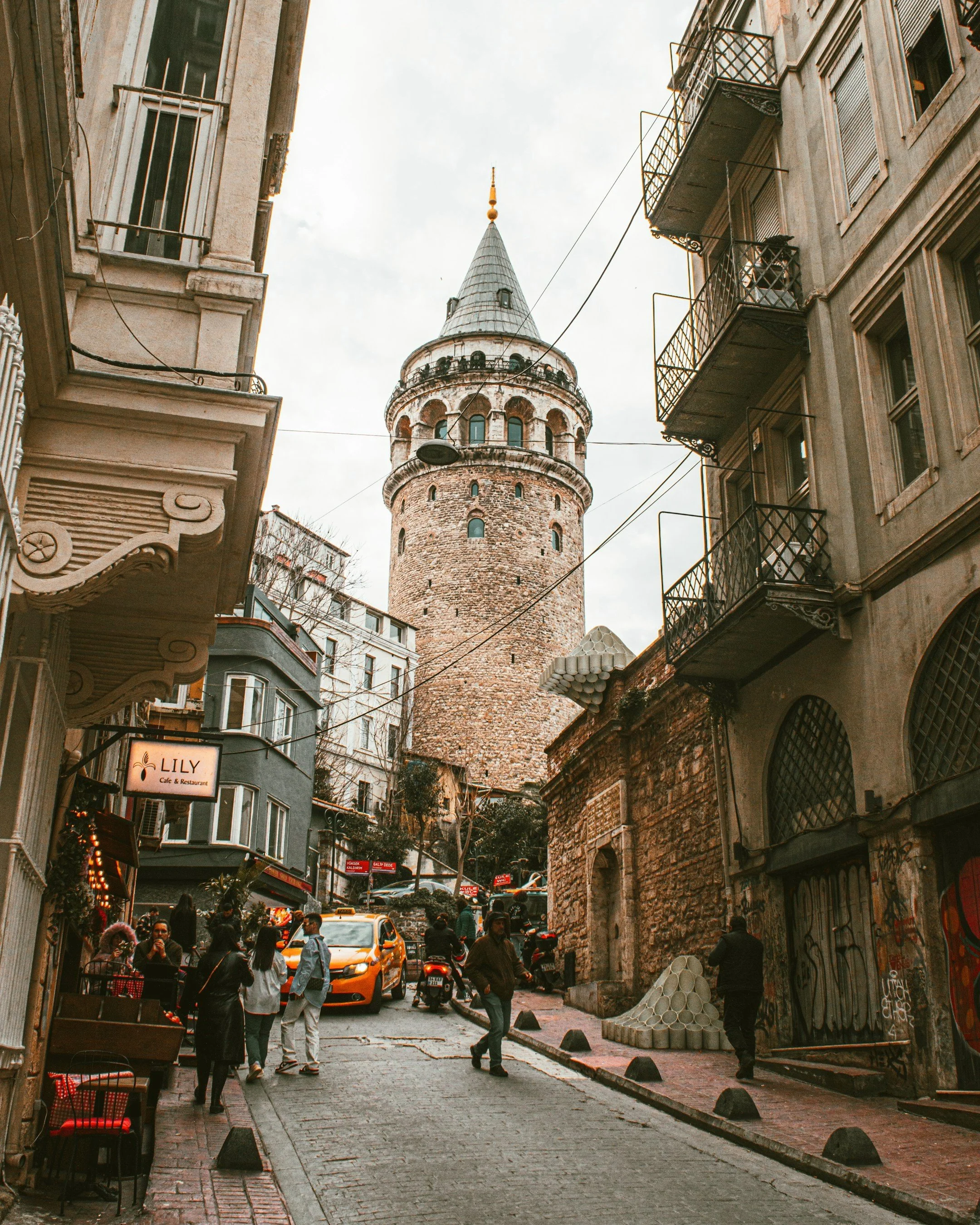 Galata Tower at the end of a narrow cobblestone street lined with historic buildings, Istanbul.