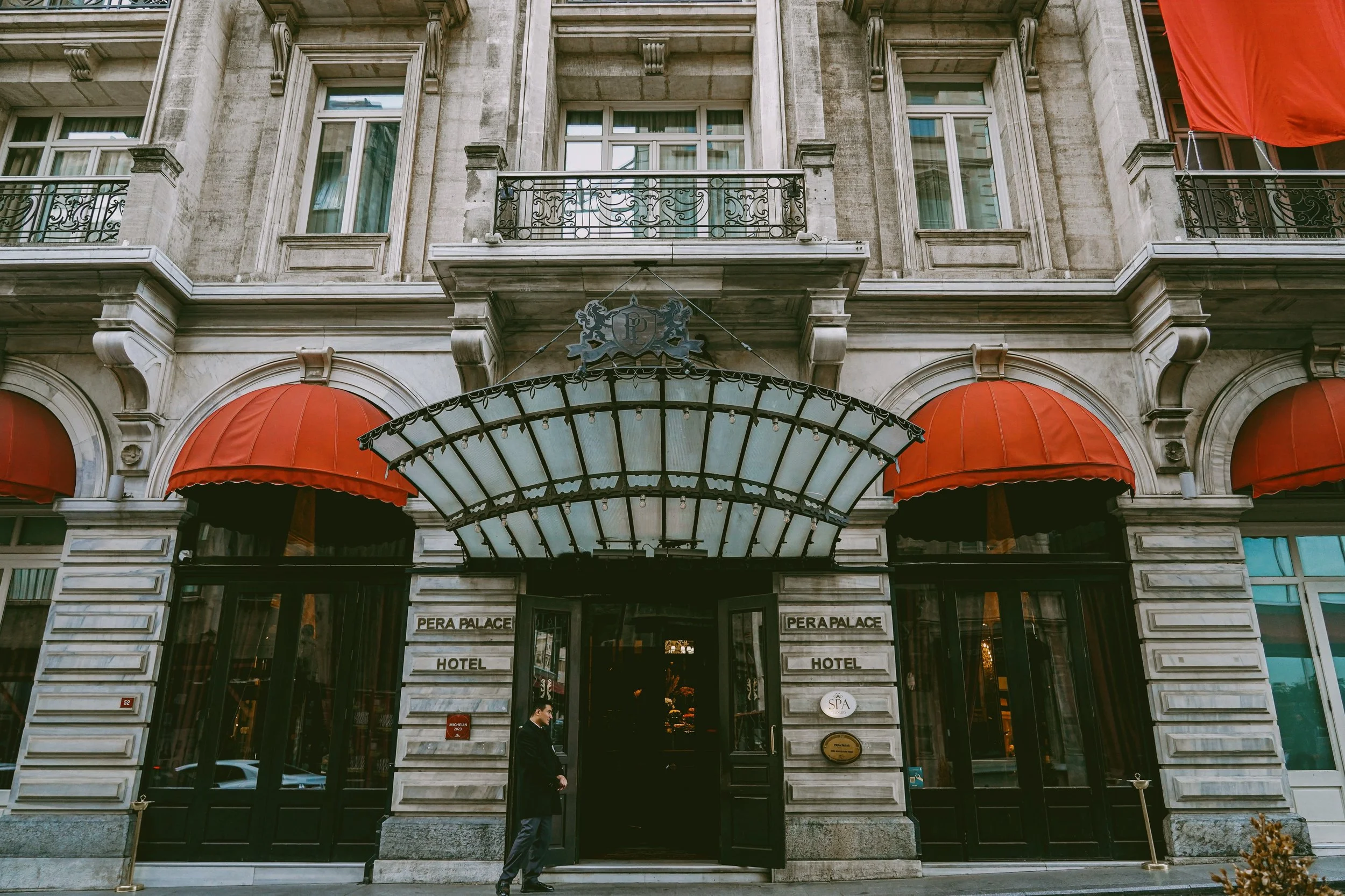 Pera Palace Hotel facade with a glass canopy over the entrance and red awnings on the ground floor, Istanbul.
