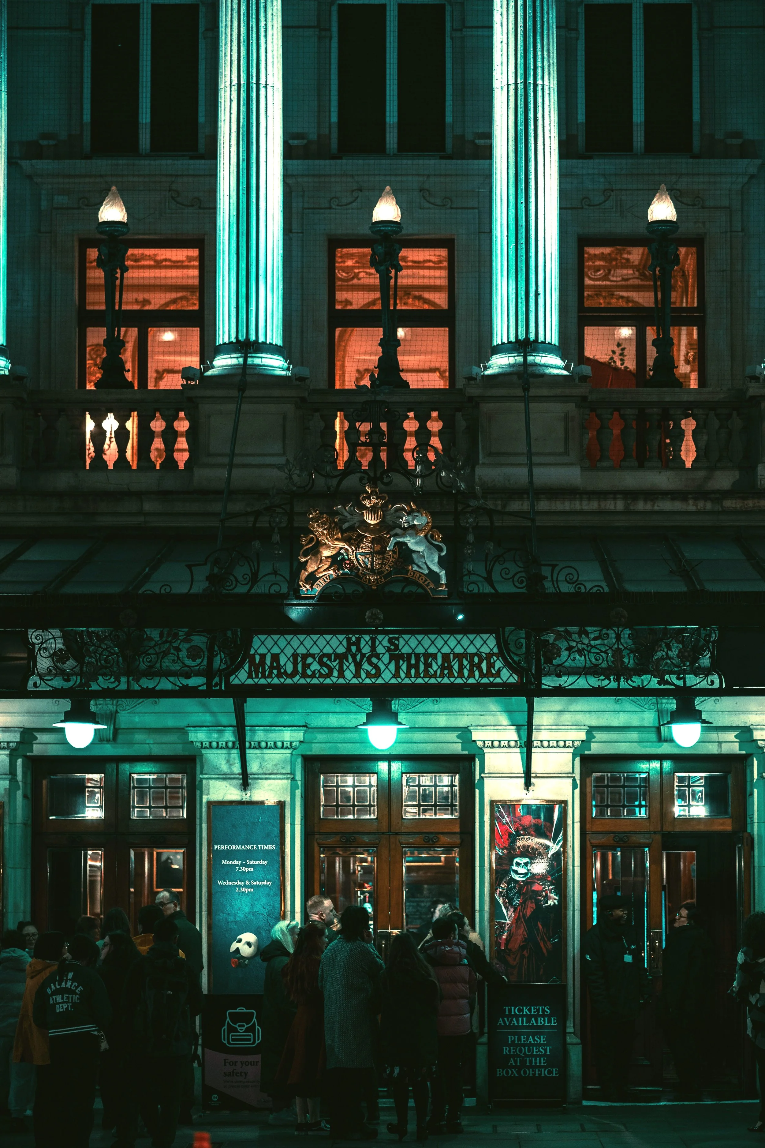 Ornate green and gold West End theatre facade lit up at night, London