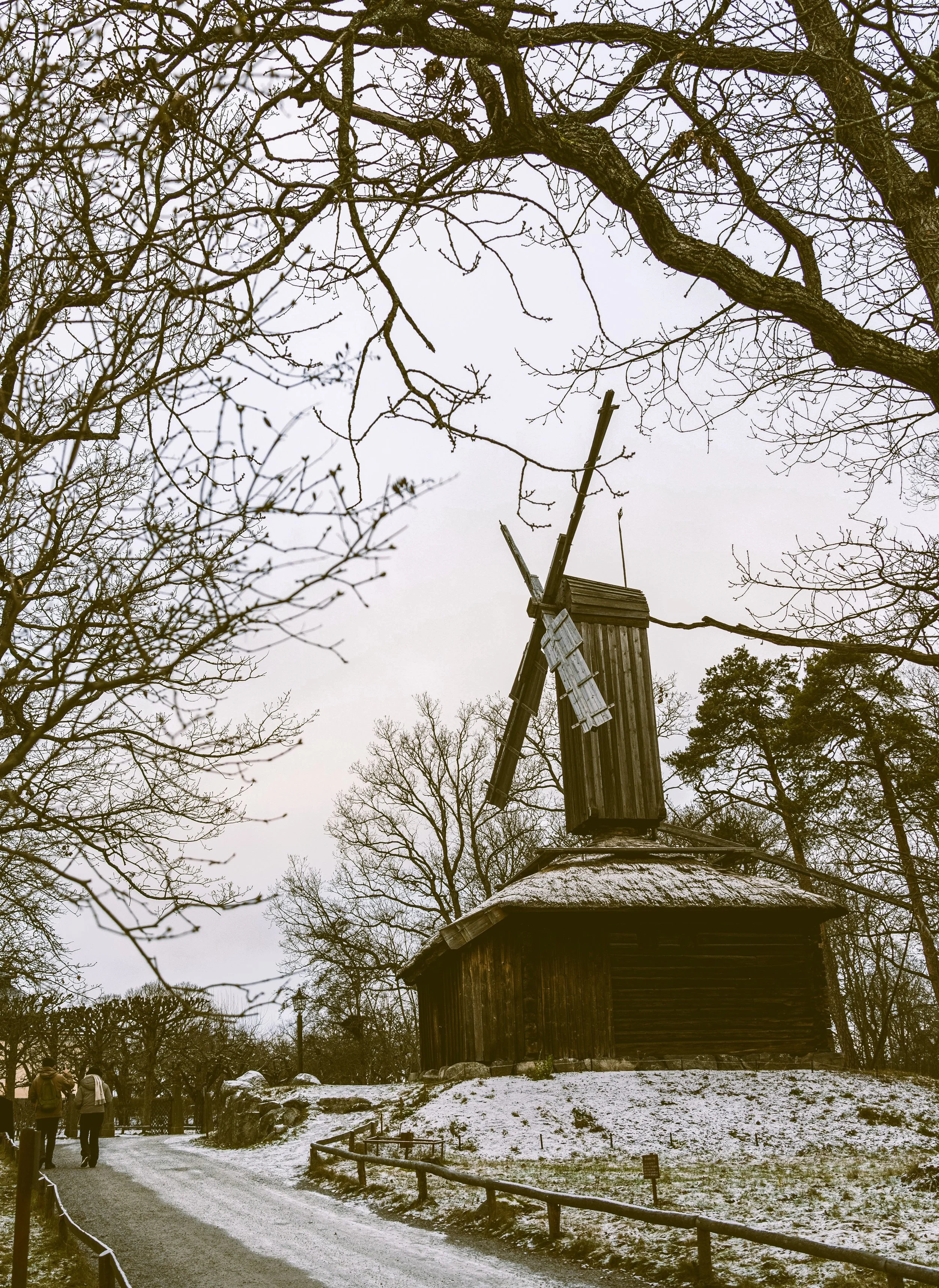 Traditional windmill among bare trees on a snowy day at Skansen, Stockholm