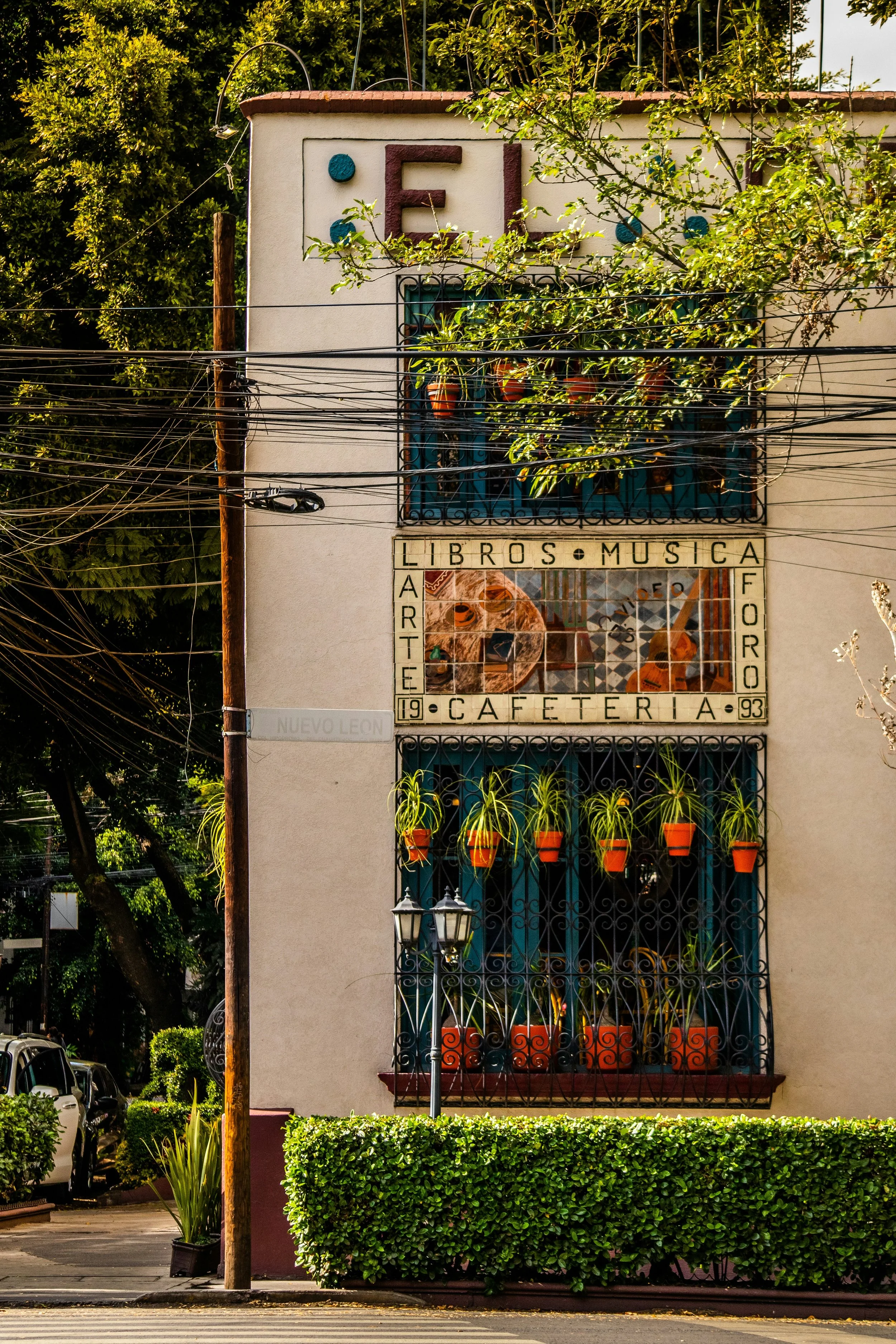 El Péndulo café exterior with its vertical garden of plants on the facade and a hedge in front, Mexico City.