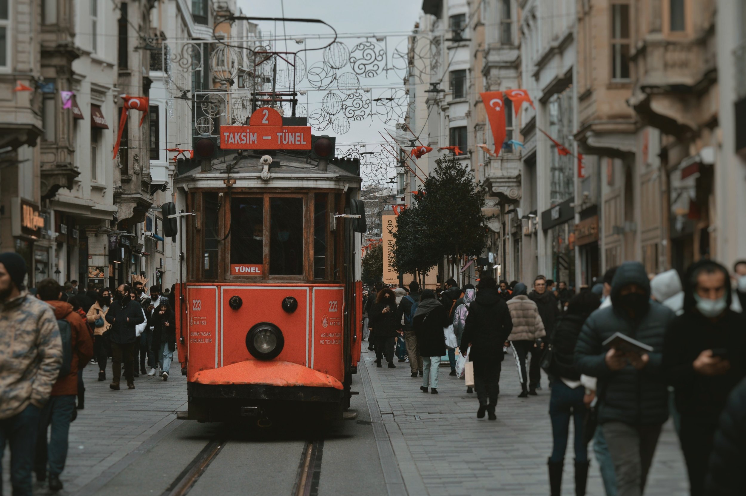 Red Taksim–Tünel vintage tram on a crowded pedestrian street with Turkish flags, Beyoglu, Istanbul