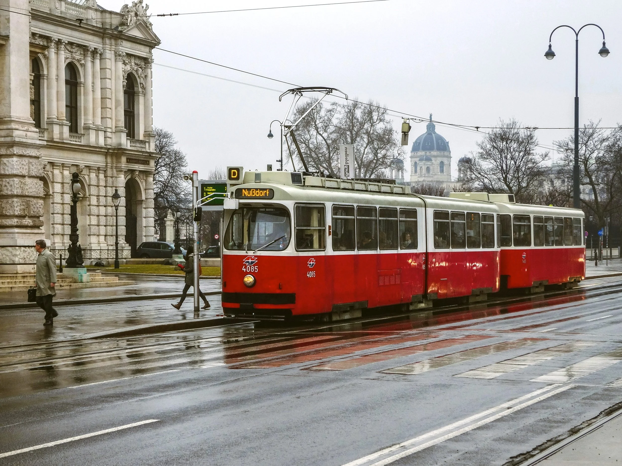 Vintage red tram on the Ringstrasse passing an ornate building, Vienna.