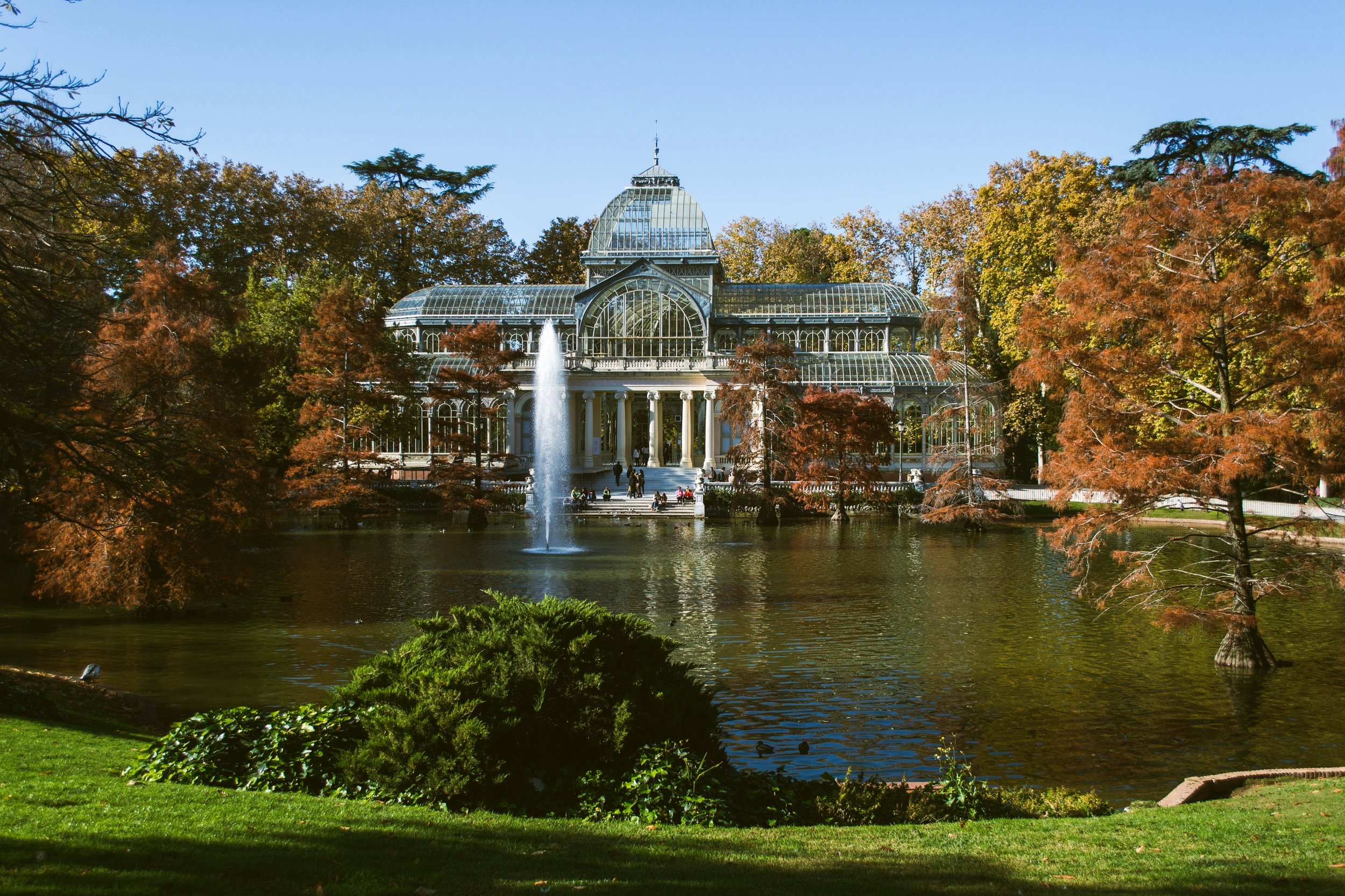 Palacio de Cristal with a fountain and autumn cypress trees at Retiro Park, Madrid