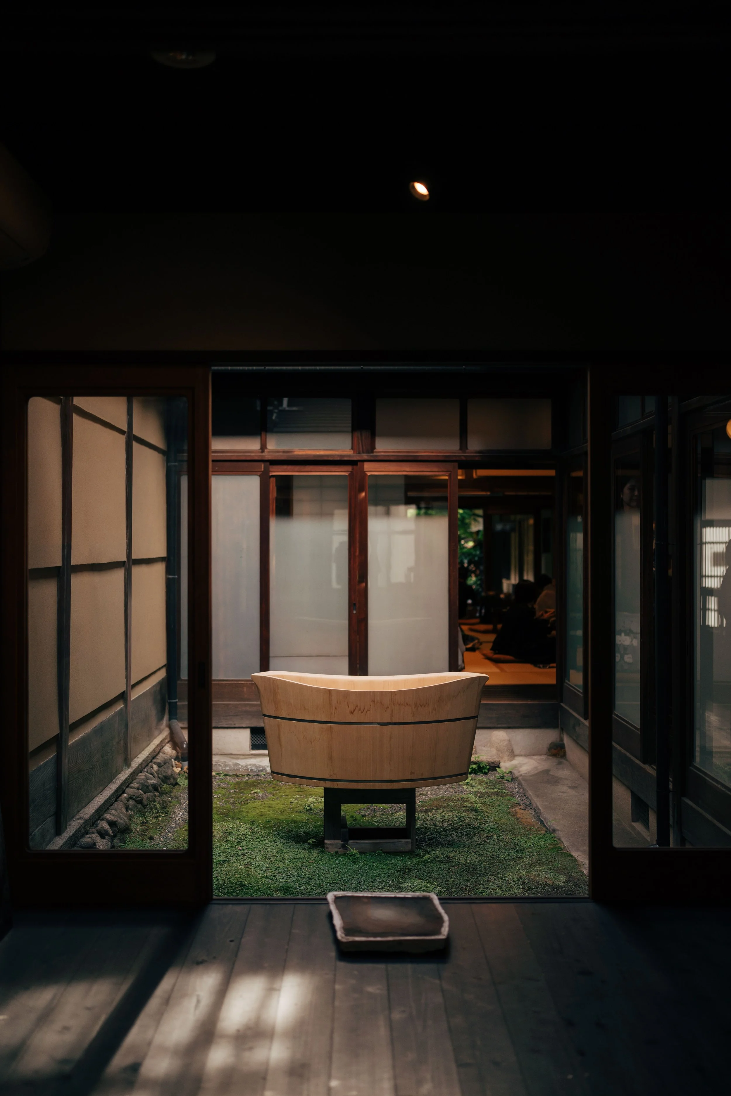 Traditional onsen with wooden sliding doors opening onto a dimly lit garden, Japan.