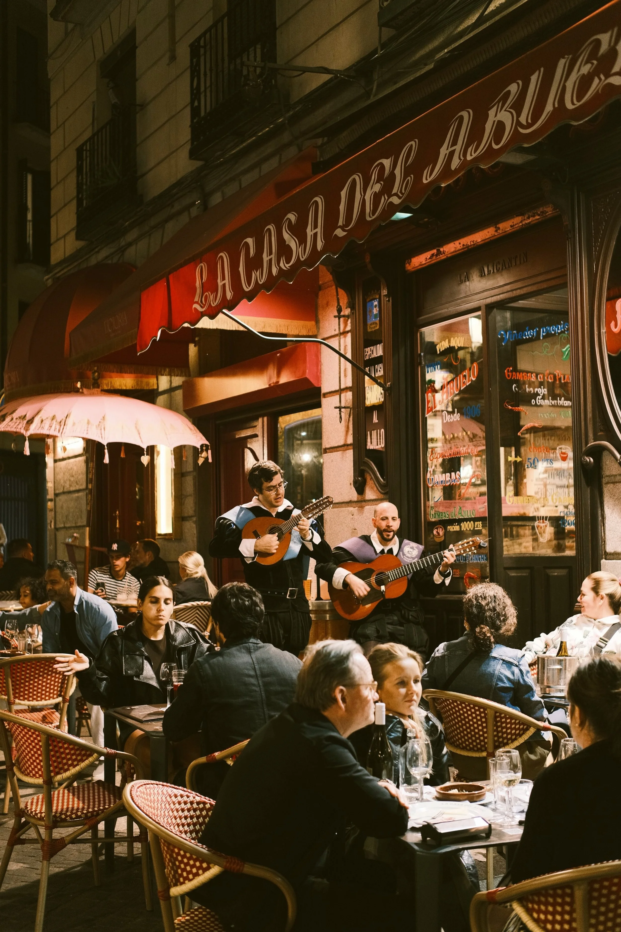 People dining on an outdoor café terrace at night in Madrid
