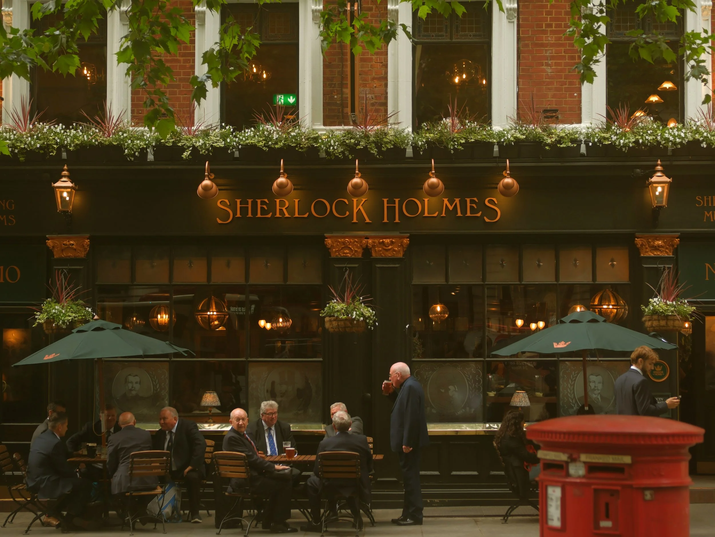 Traditional pub facade with hanging plants and outdoor seating, London.
