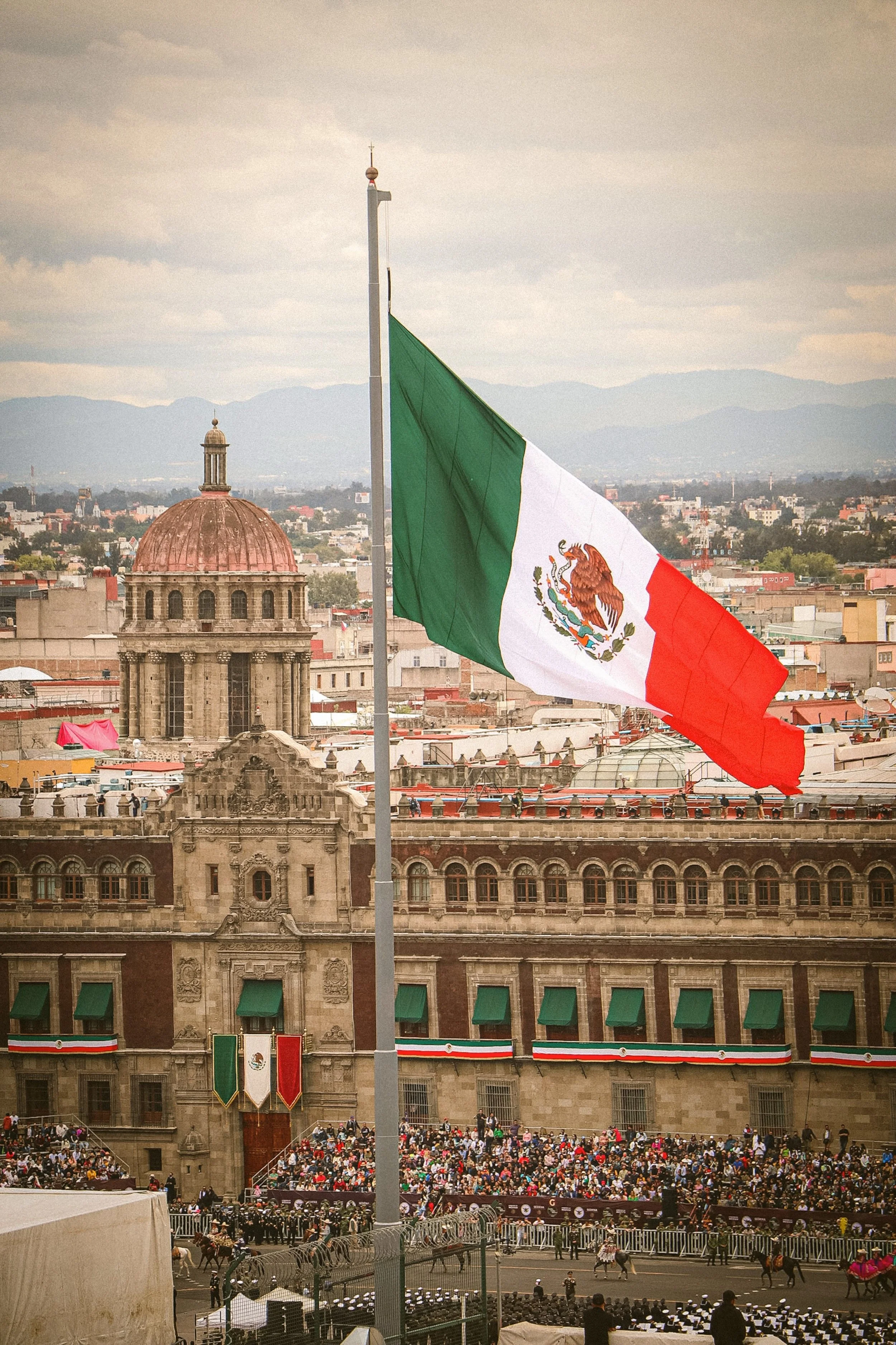 Mexican flag flying over the Zócalo with historic buildings behind, Mexico City.