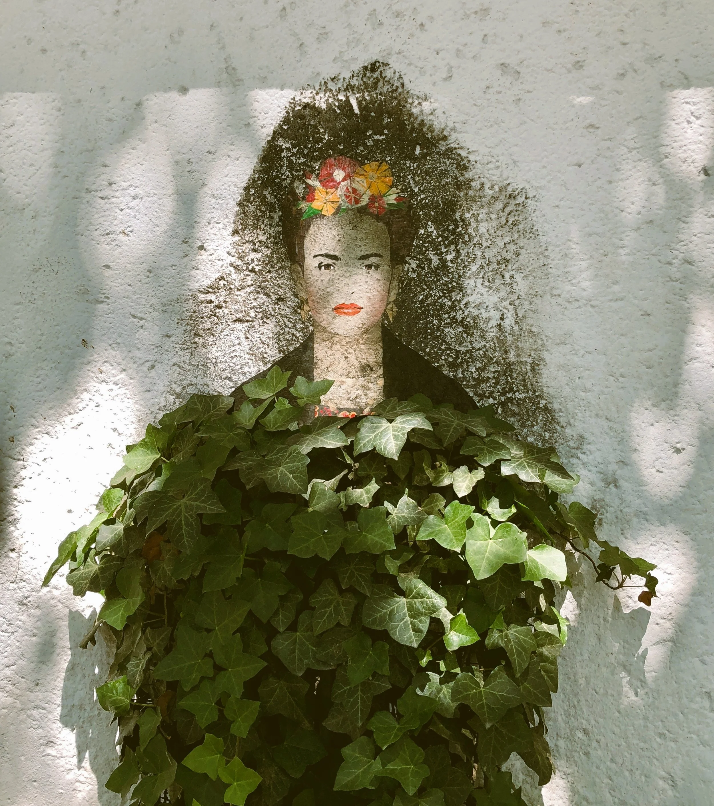 Portrait of Frida Kahlo partly covered by green leaves, Mexico City.