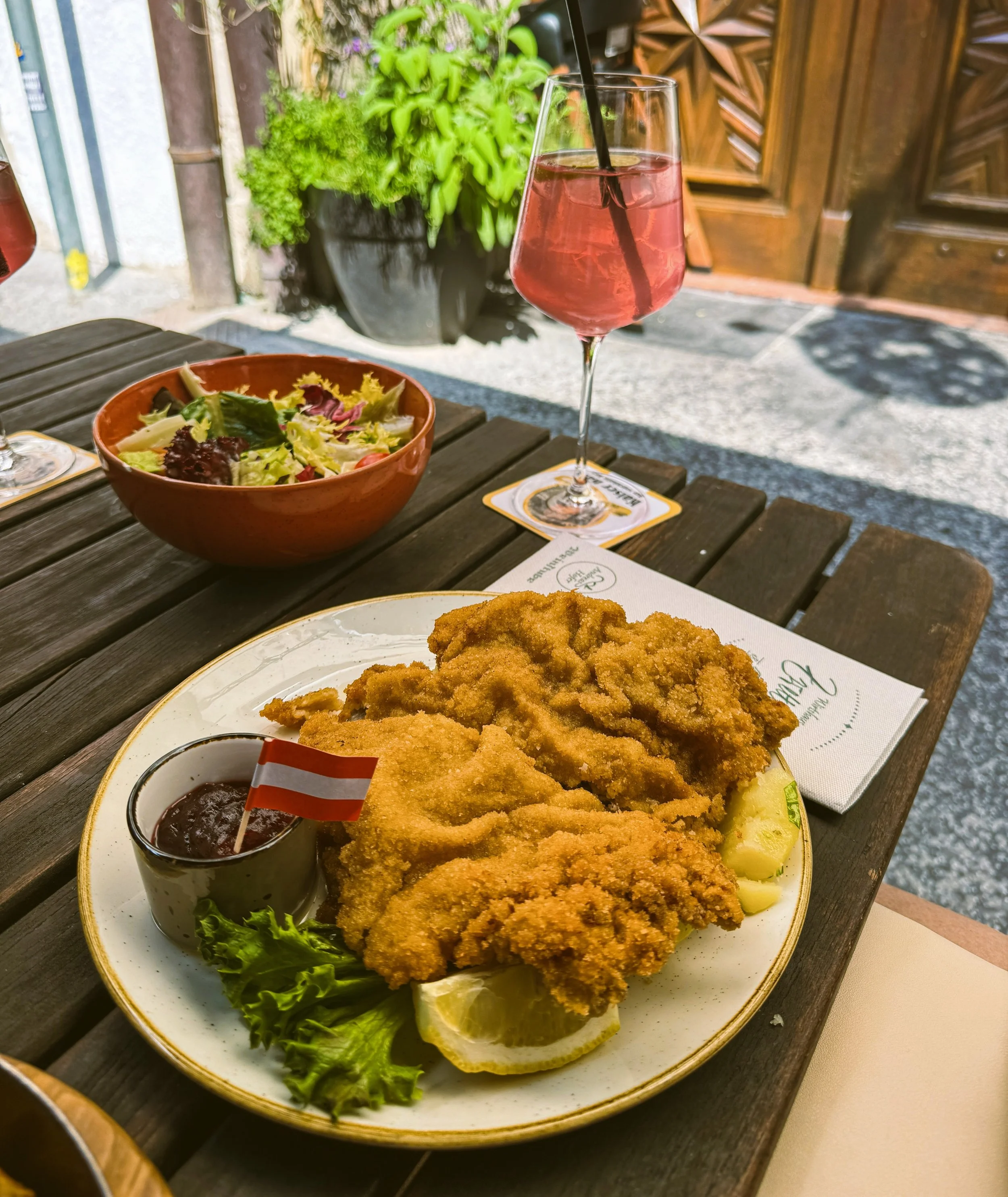 Wiener schnitzel served on a plate with salad in the background.